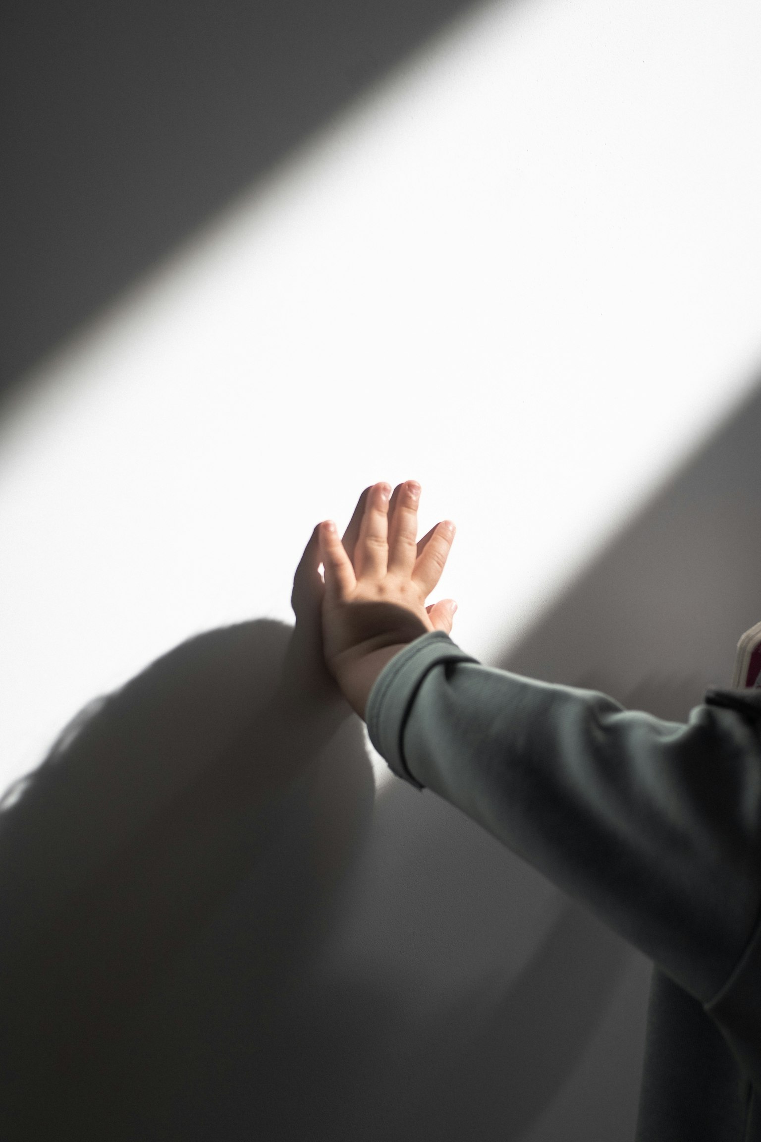 มือที่ยื่นออกไปสัมผัสผนังที่ถูกแสงนุ่มส่องสว่าง