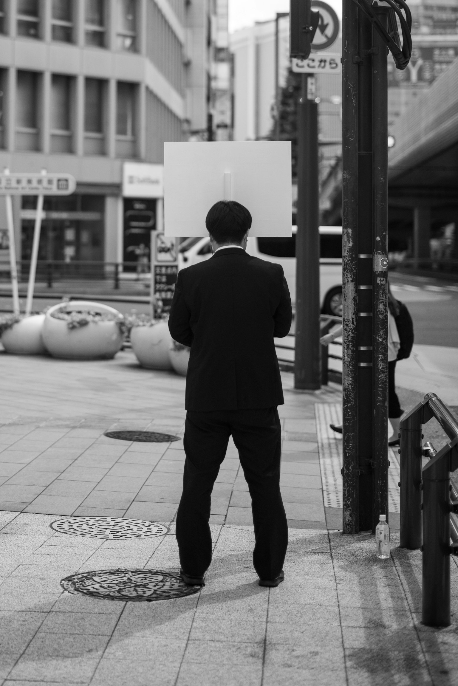 Un uomo in un abito nero che sta in un angolo di strada