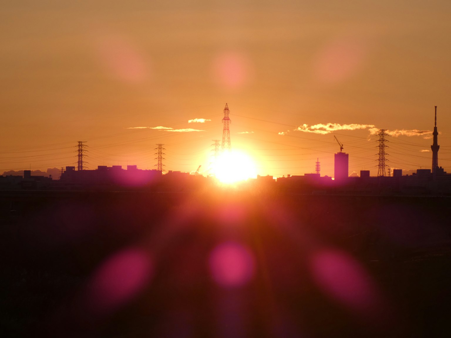 Puesta de sol proyectando siluetas de edificios y torres contra un cielo colorido