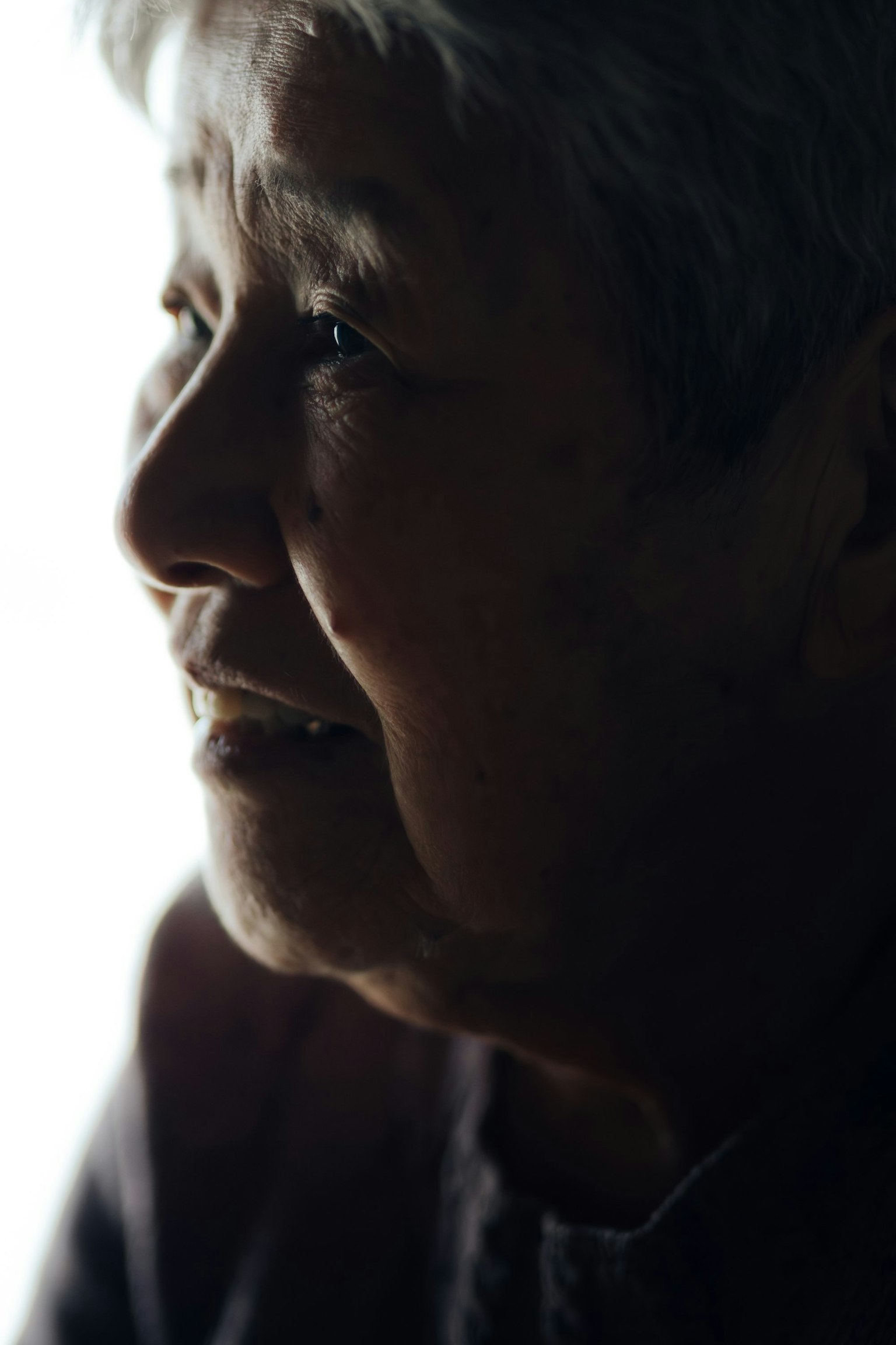 Perfil de una mujer anciana sonriendo contra un fondo brillante