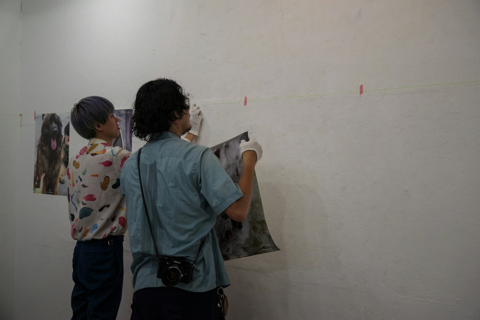 Hai nghệ sĩ treo tác phẩm nghệ thuật trên tường trắng