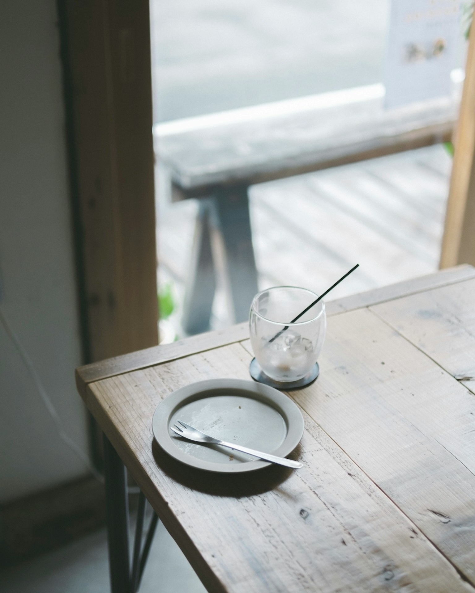 Escena de café simple con un plato y un vaso en una mesa de madera