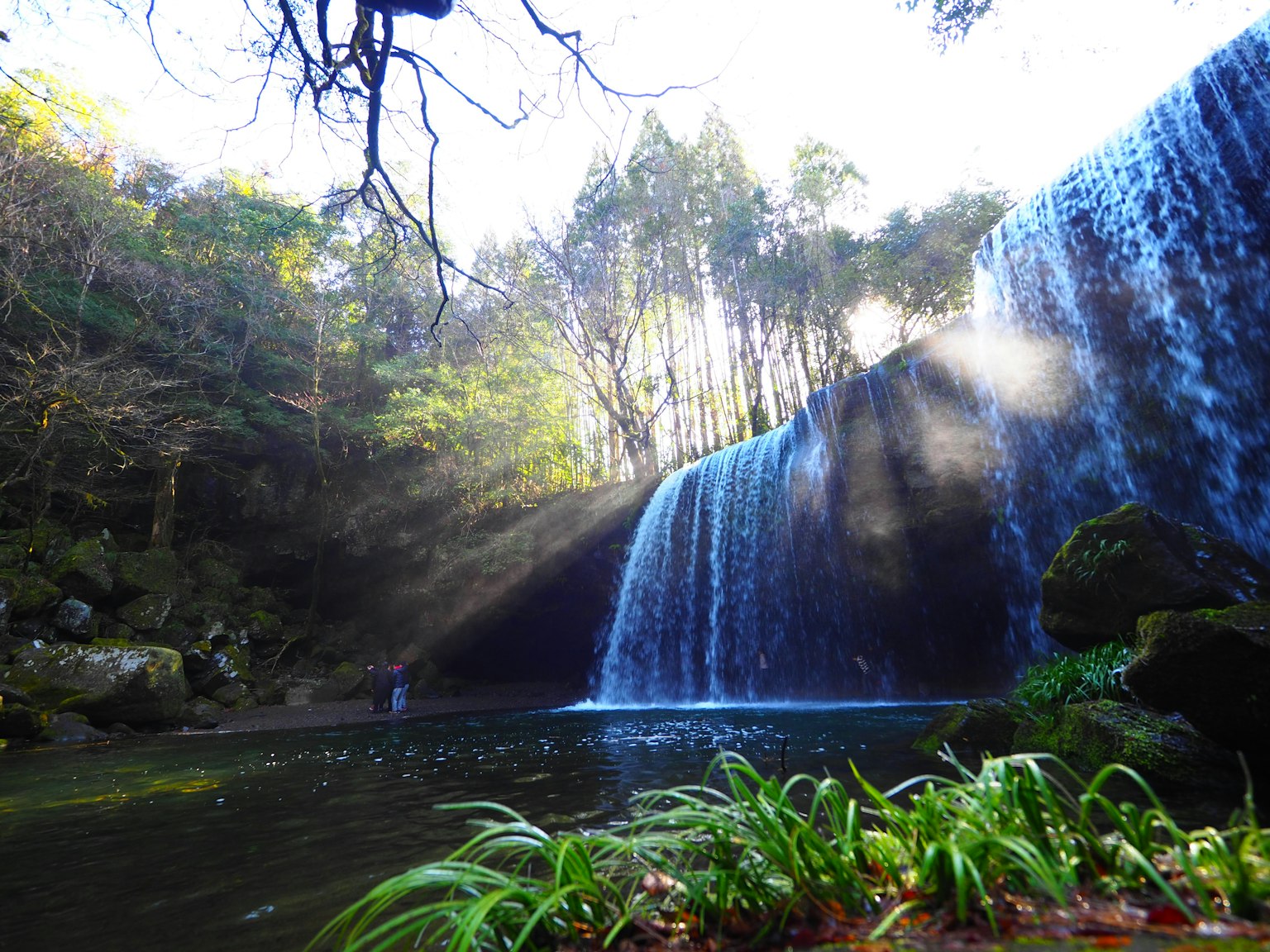 Air terjun yang indah dikelilingi oleh pepohonan rimbun dengan efek kabut dan cahaya
