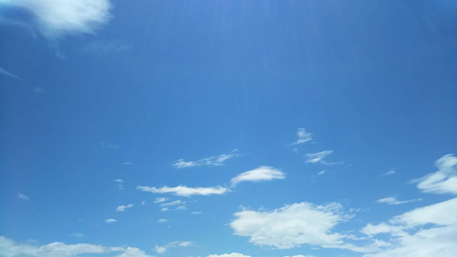 A clear blue sky with scattered white clouds