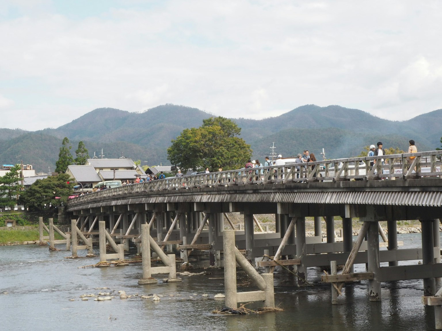 สะพานไม้ข้ามแม่น้ำพร้อมภูเขาในพื้นหลัง