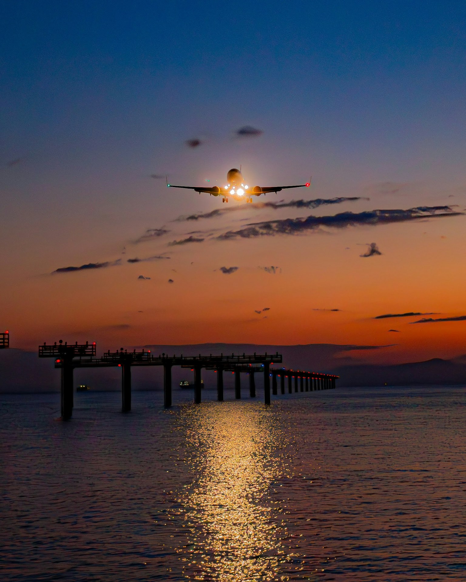 Molo sull'acqua al tramonto con riflesso della luna