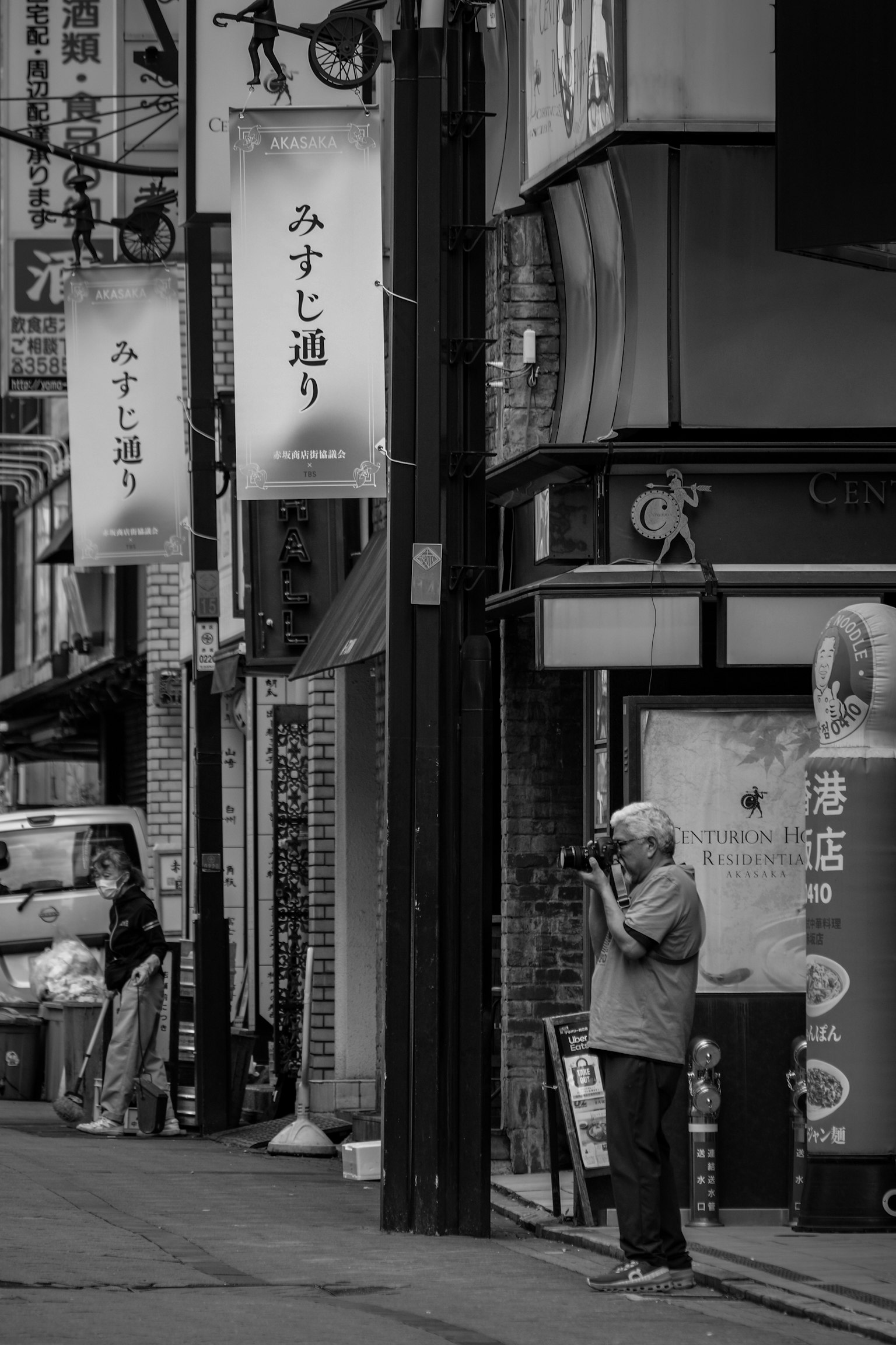 一名男子在街角拿著相機,黑白商店招牌