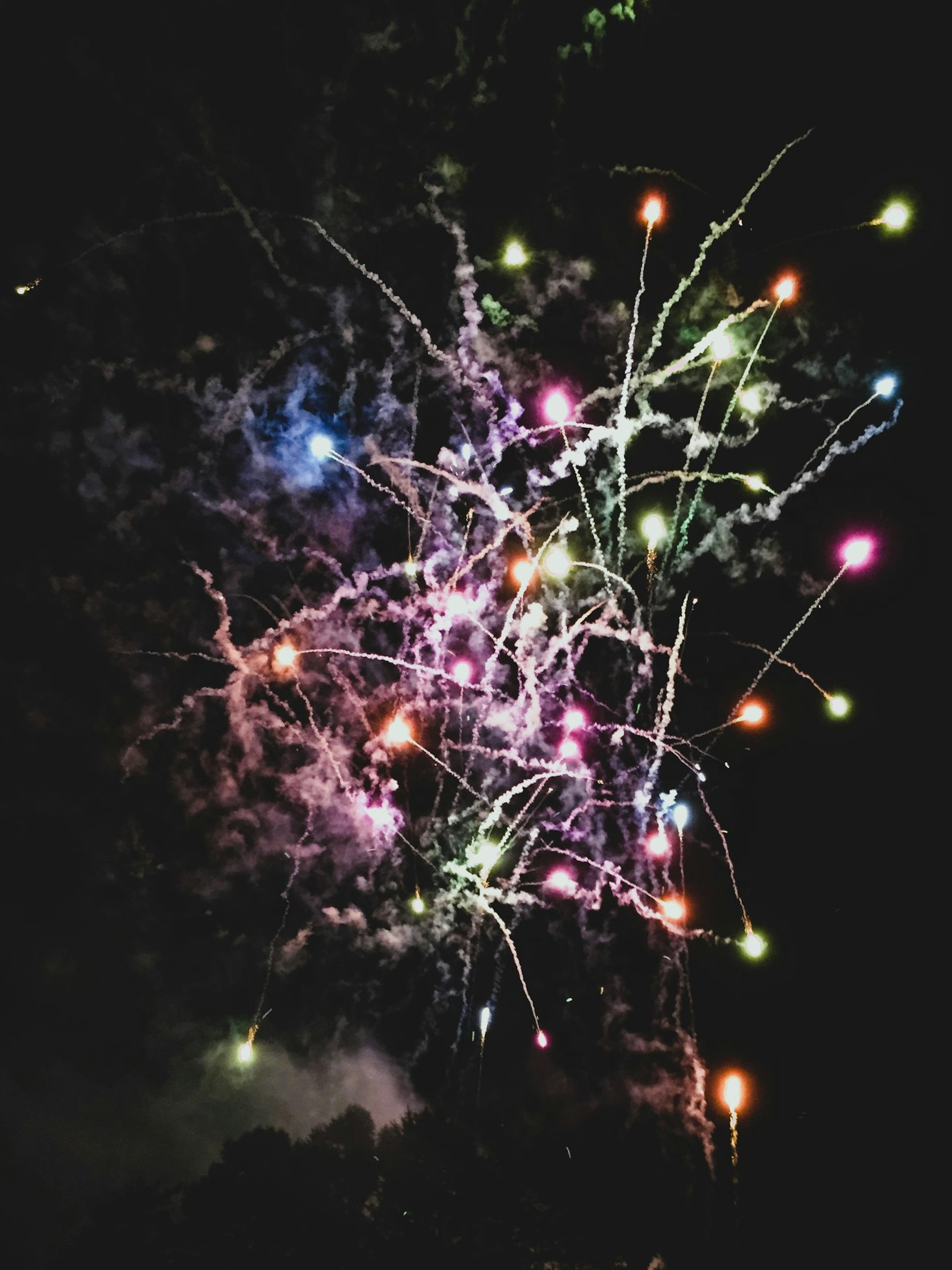 Colorful fireworks exploding in the night sky with trails of light