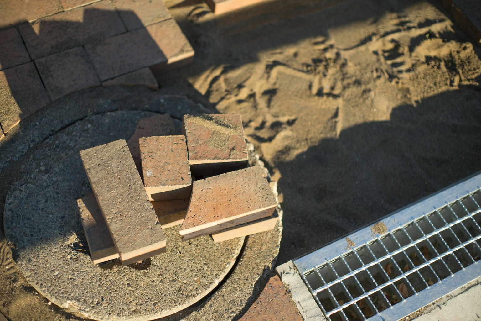 Imagen de ladrillos apilados sobre una base circular de concreto en arena