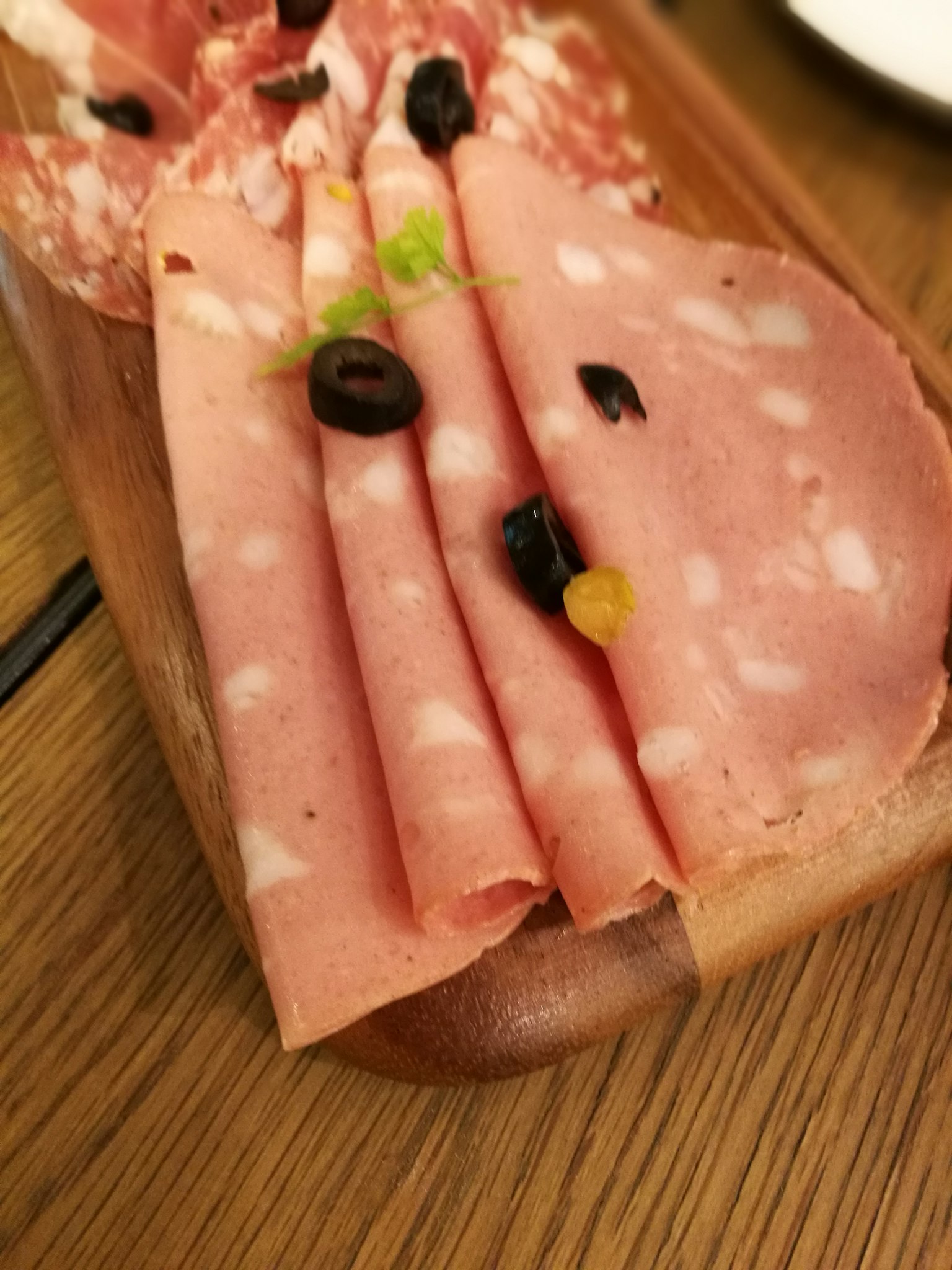 Vassoio di prosciutto affettato con olive su un tagliere di legno