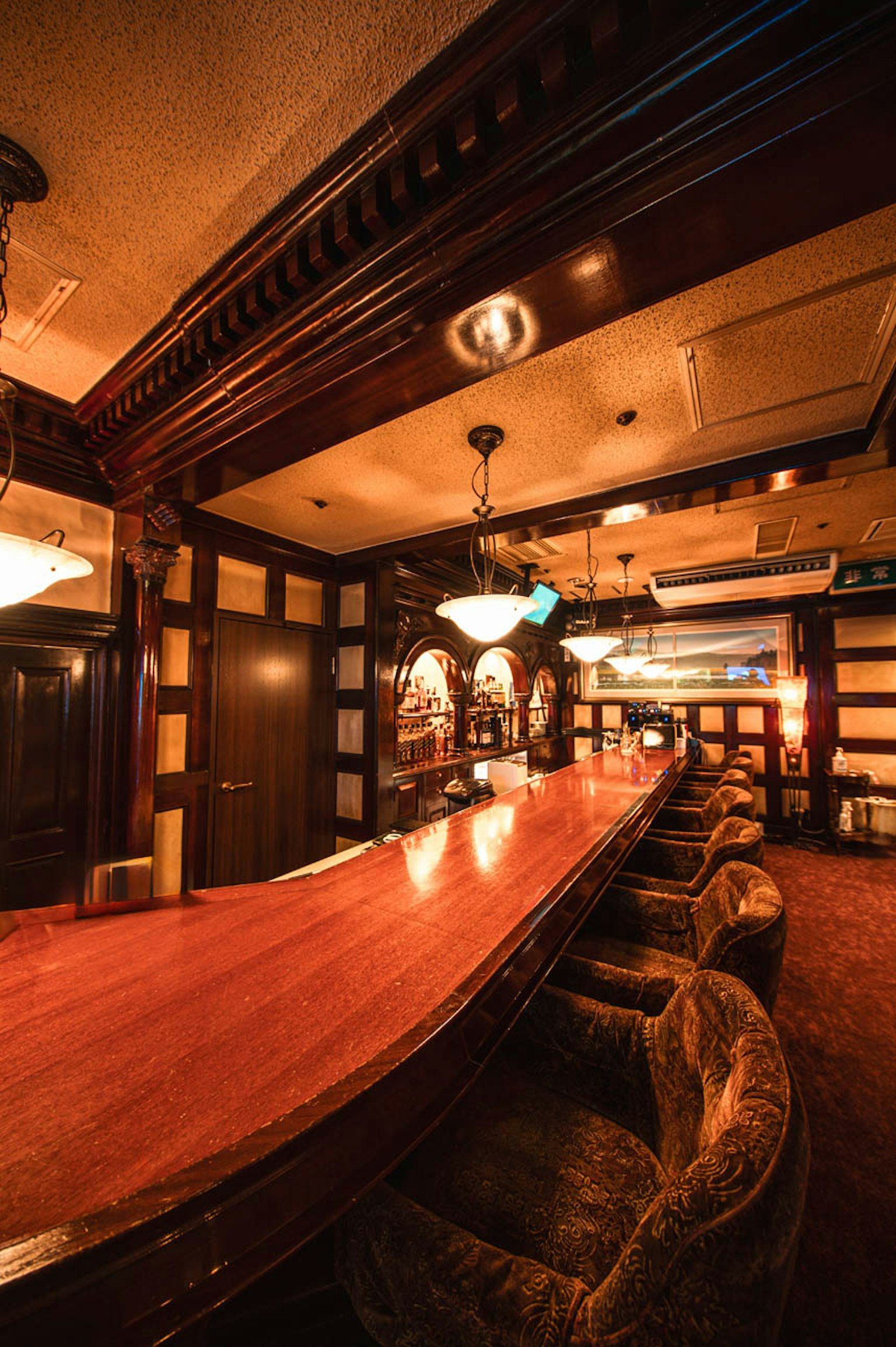 Interior elegante de bar con largo mostrador de madera asientos acolchados iluminación cálida y detalles de madera decorativos
