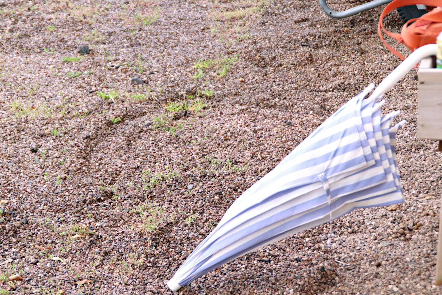 Blue and white striped umbrella resting on the ground
