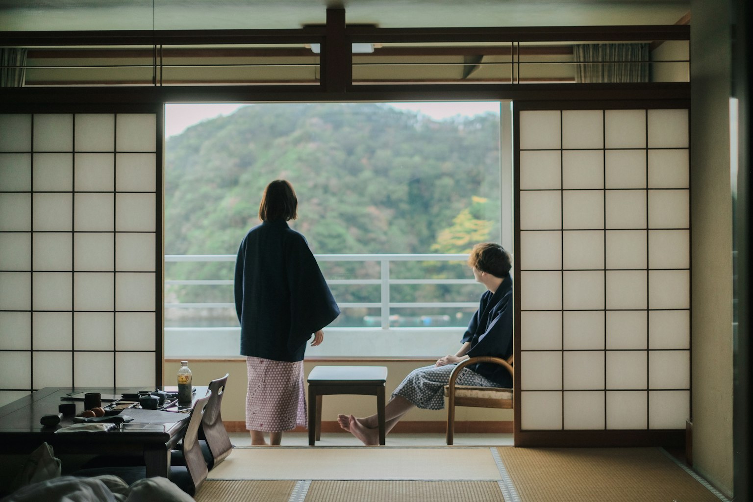 兩位女性在傳統日本房間內放鬆，窗外是美麗的山景