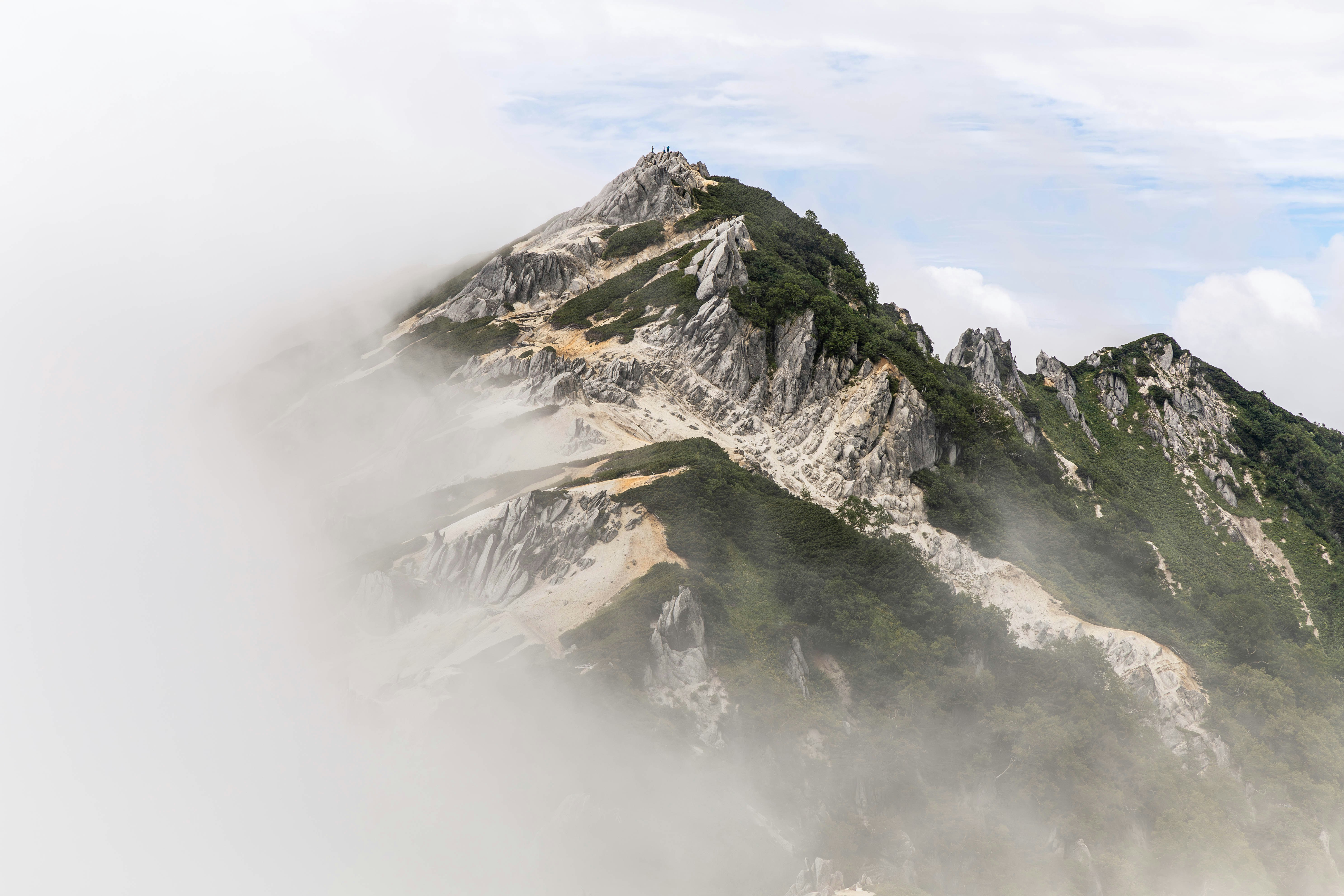 Bergkamm mit felsigen Gipfeln, die im Nebel hervortreten
