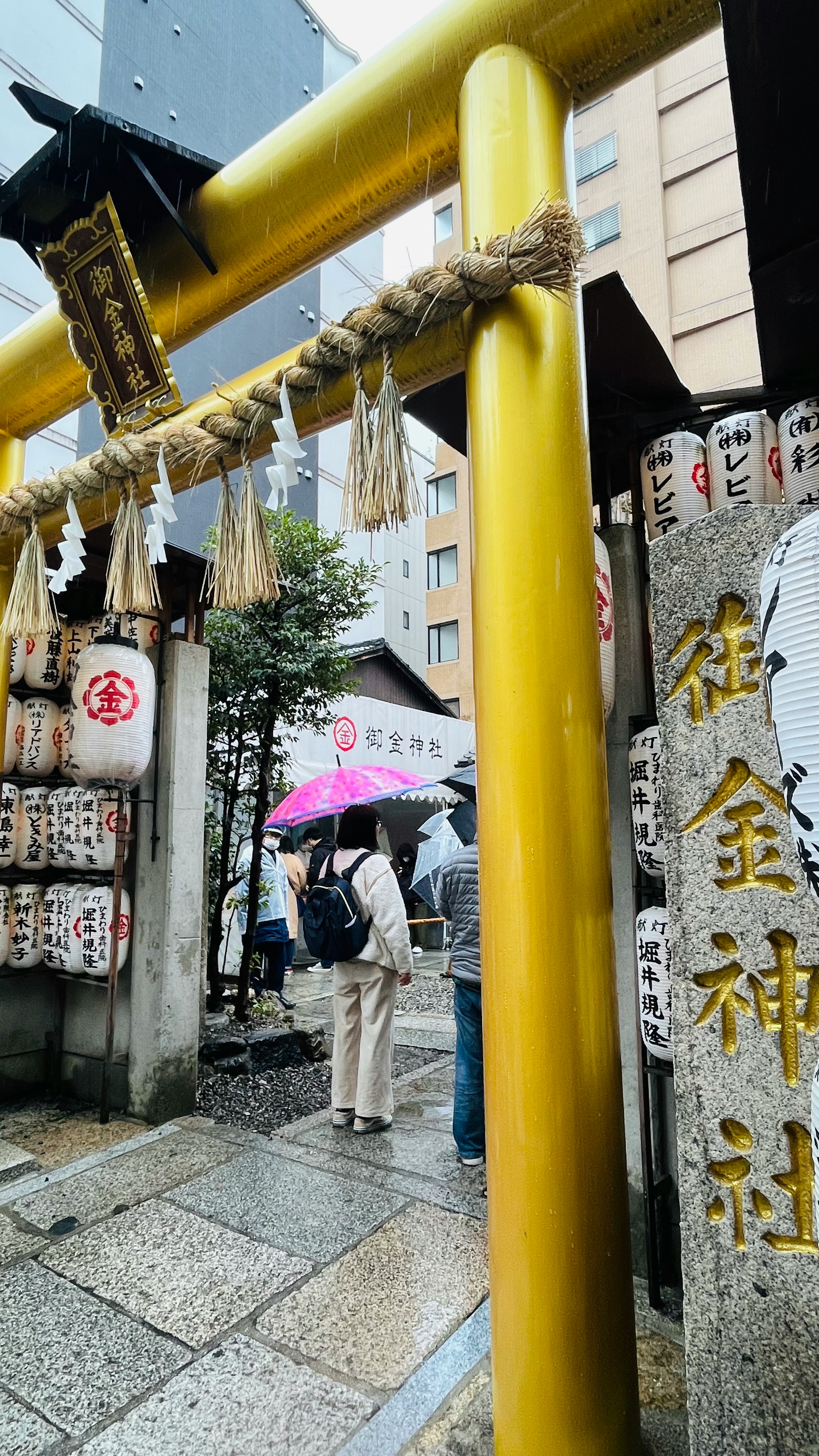 yellow torii gate with rows of omamori charms along a shrine approach