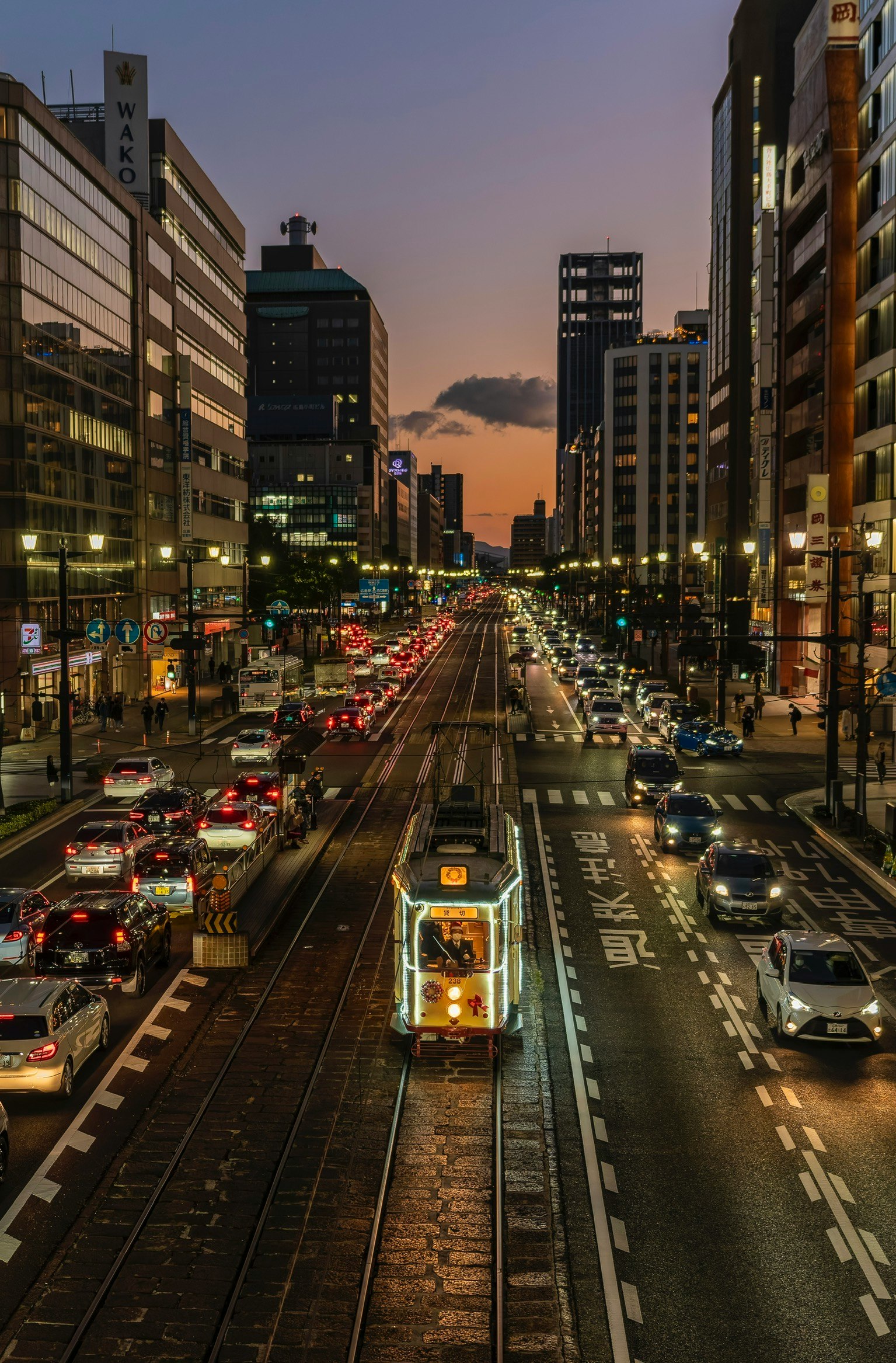 夕焼け空の下を走る路面電車のある大通り