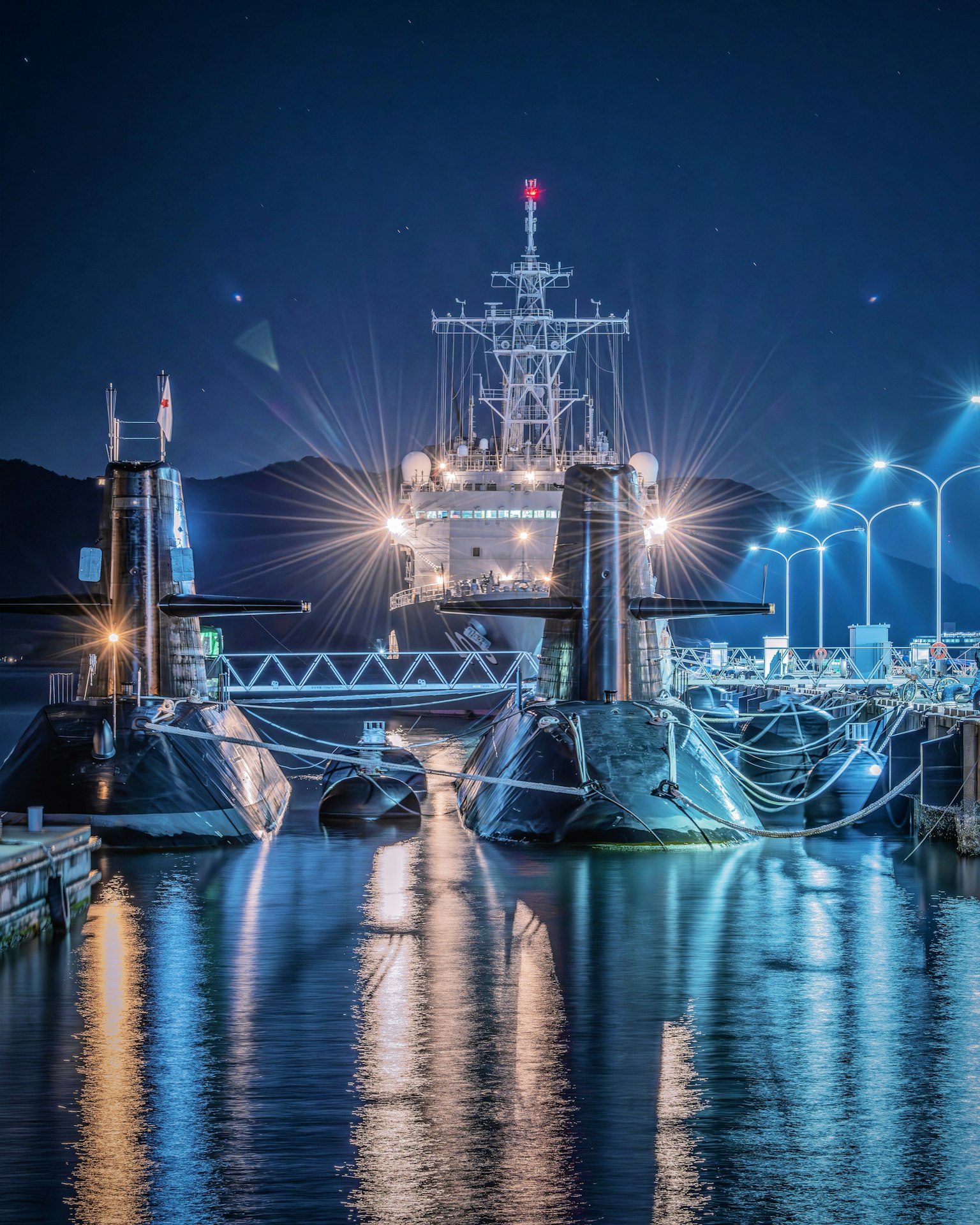 Sous-marins amarrés la nuit avec des reflets dans l'eau et des lumières vives