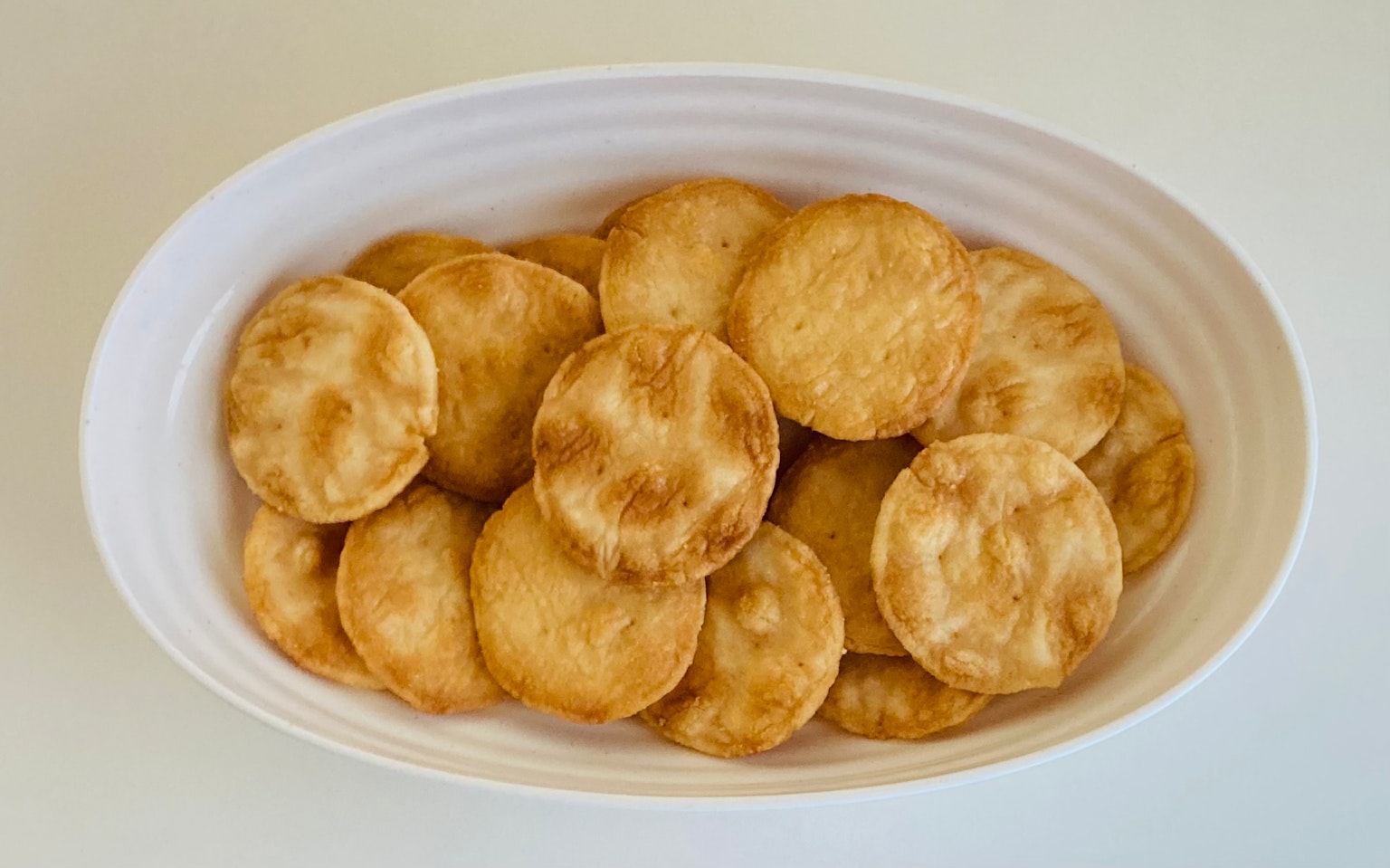 A collection of round crackers arranged in a white bowl