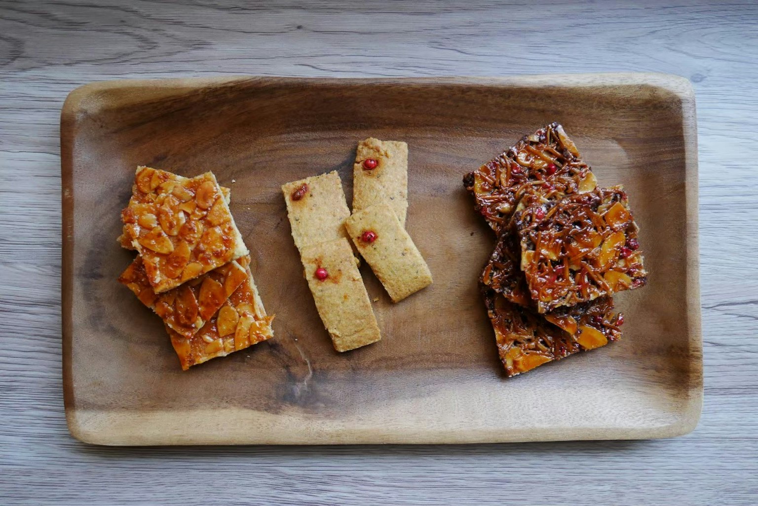 Pemanis yang terbuat dari kacang dan karamel di atas piring kayu