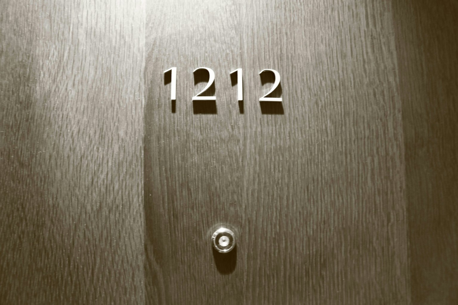 Porta in legno con il numero 1212 e un occhio di bue