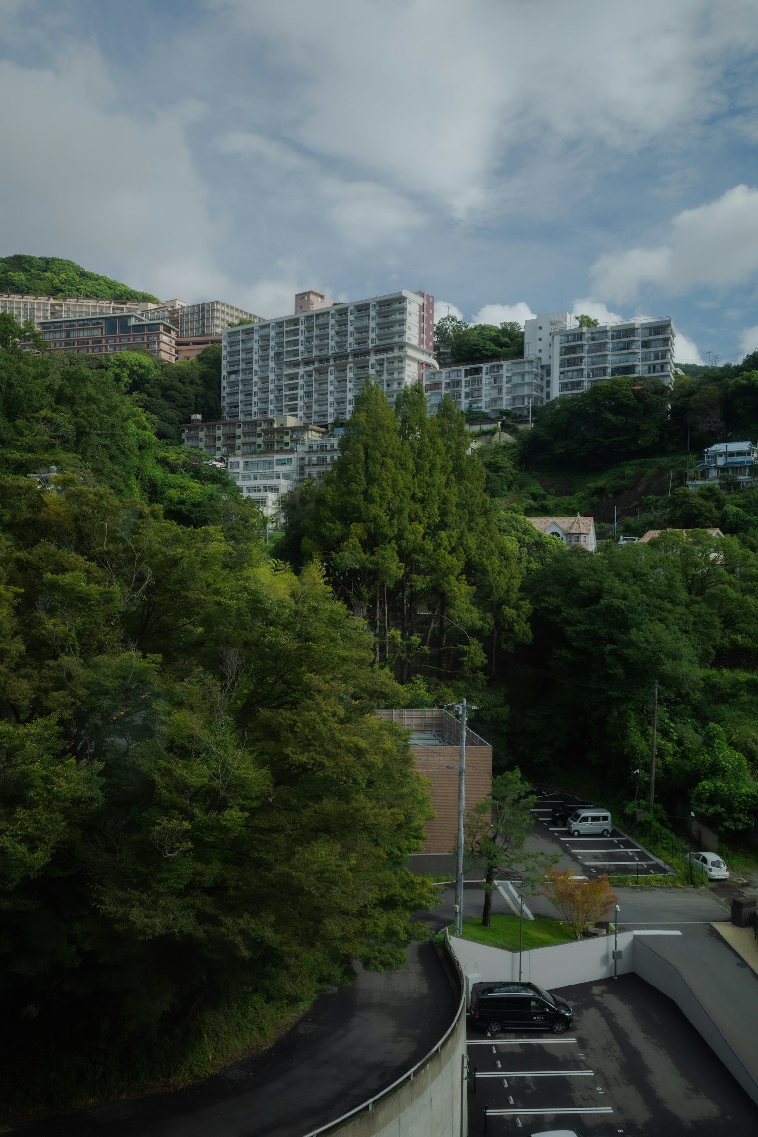 Vue pittoresque d'appartements en hauteur sur une colline verdoyante avec un parking