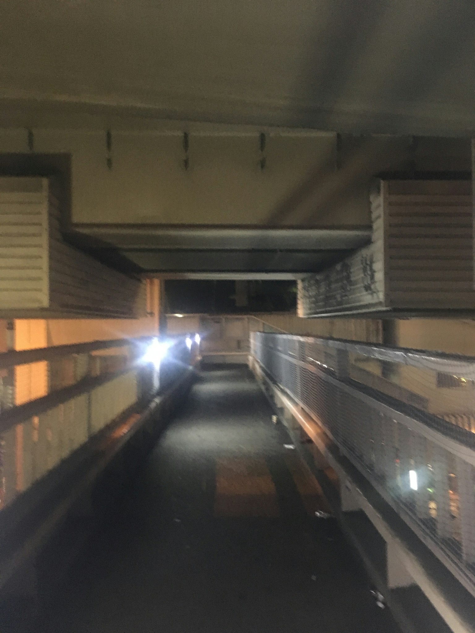 Lorong panjang dengan pegangan kaca dan pencahayaan redup