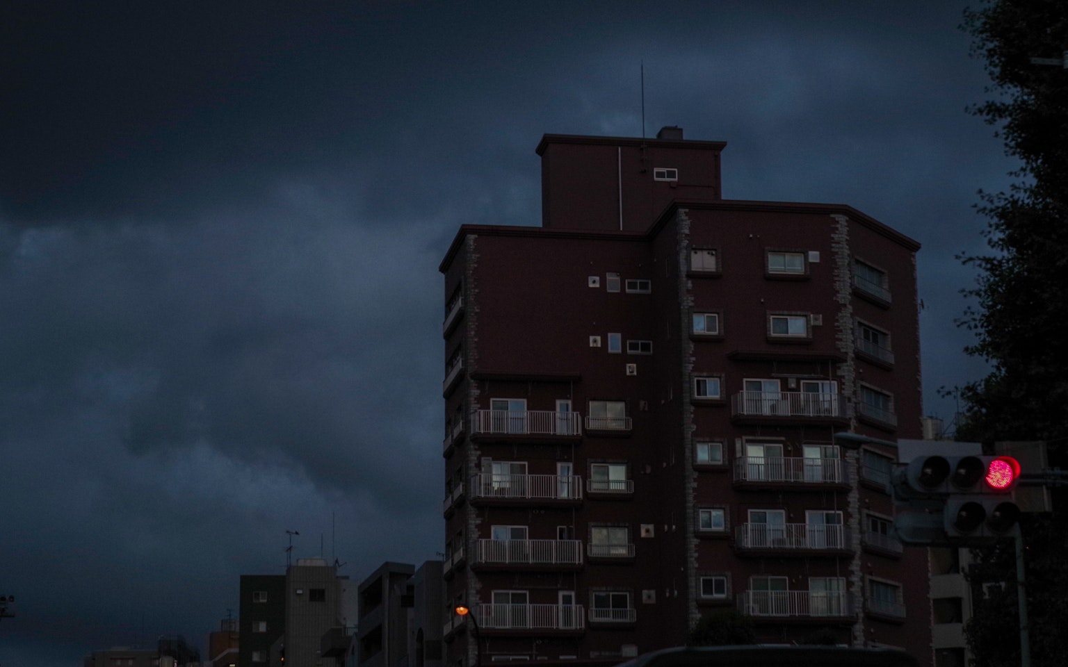 Paysage urbain sous des nuages sombres avec un immeuble et un feu rouge