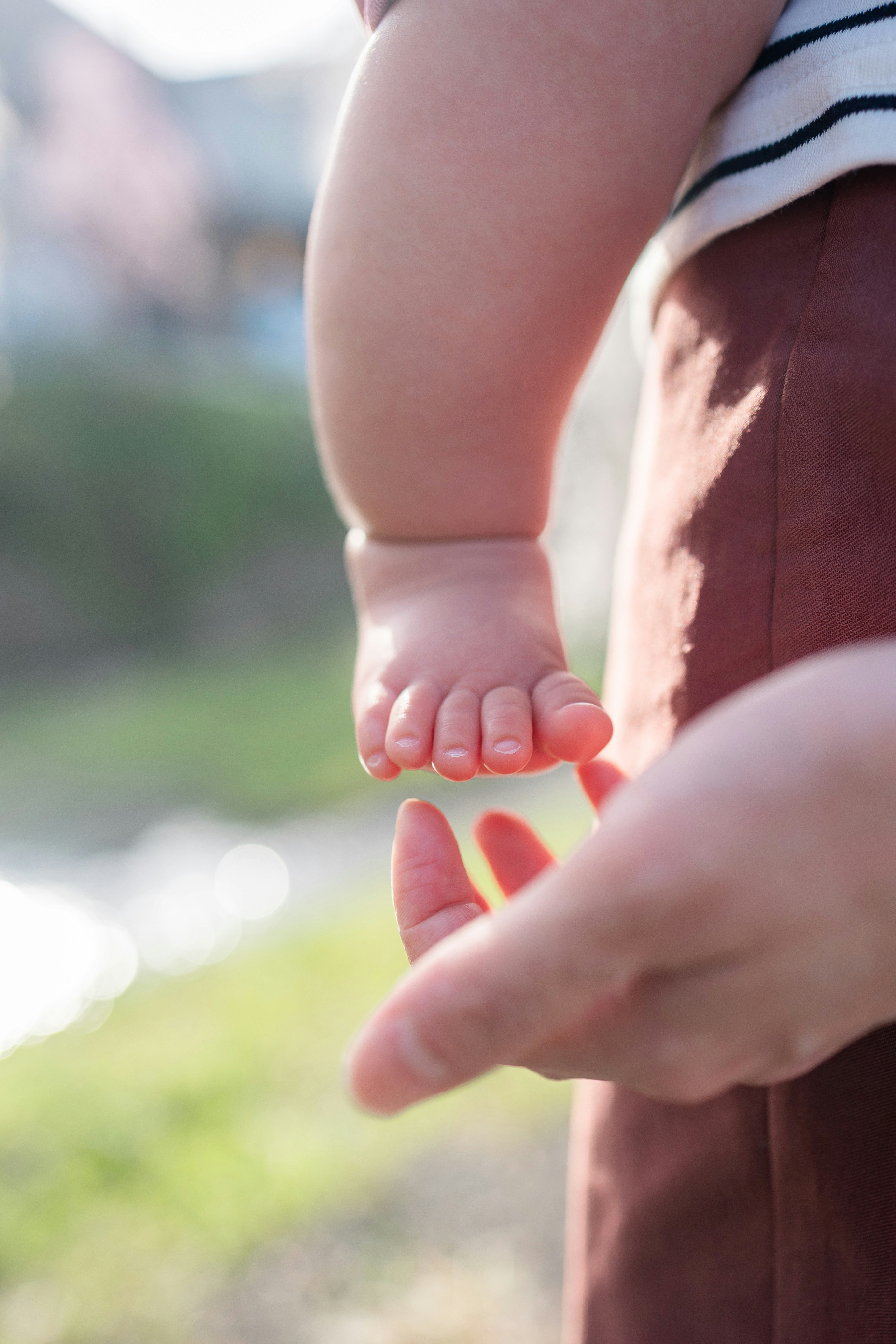 momento affettuoso in primo piano: i piedini di un bambino e la mano di un adulto