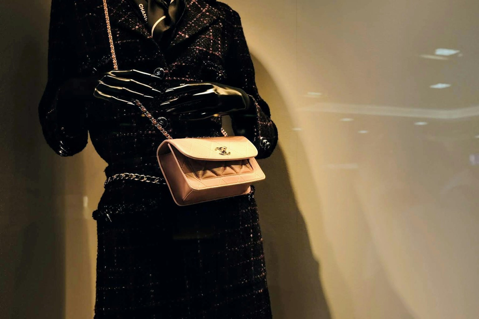 Un manichino vestito con un completo nero che tiene una borsa rosa