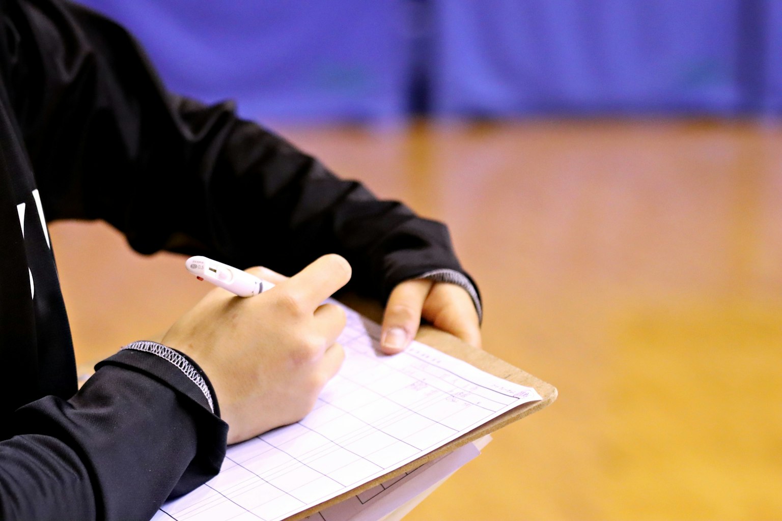 Person writing notes on a clipboard with a pen