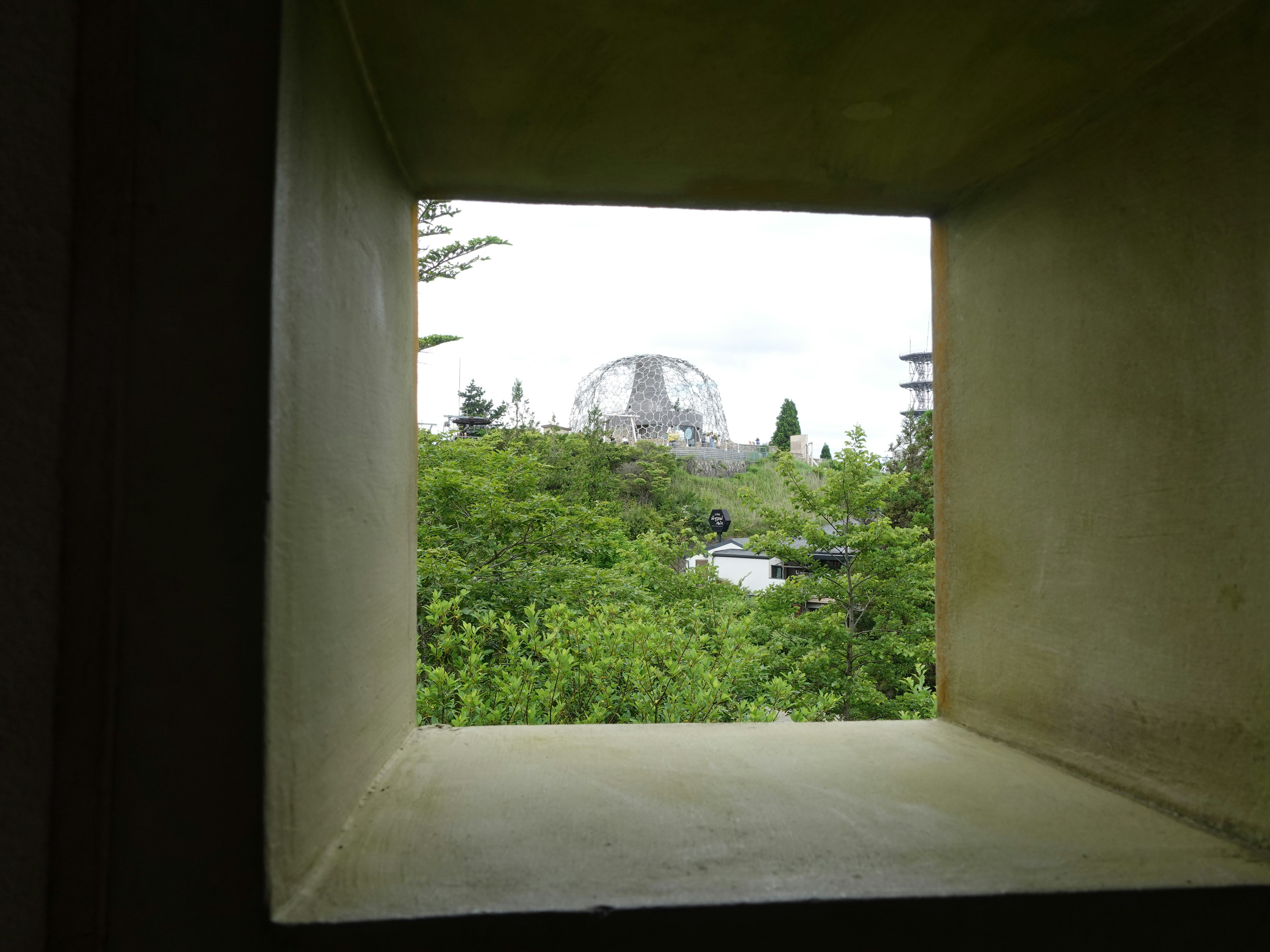 View from a window showing green landscape and a dome-shaped structure