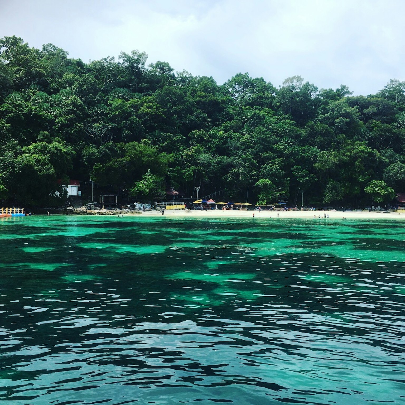 Vista panoramica di acqua blu e foresta verdeggiante con capanne sulla spiaggia