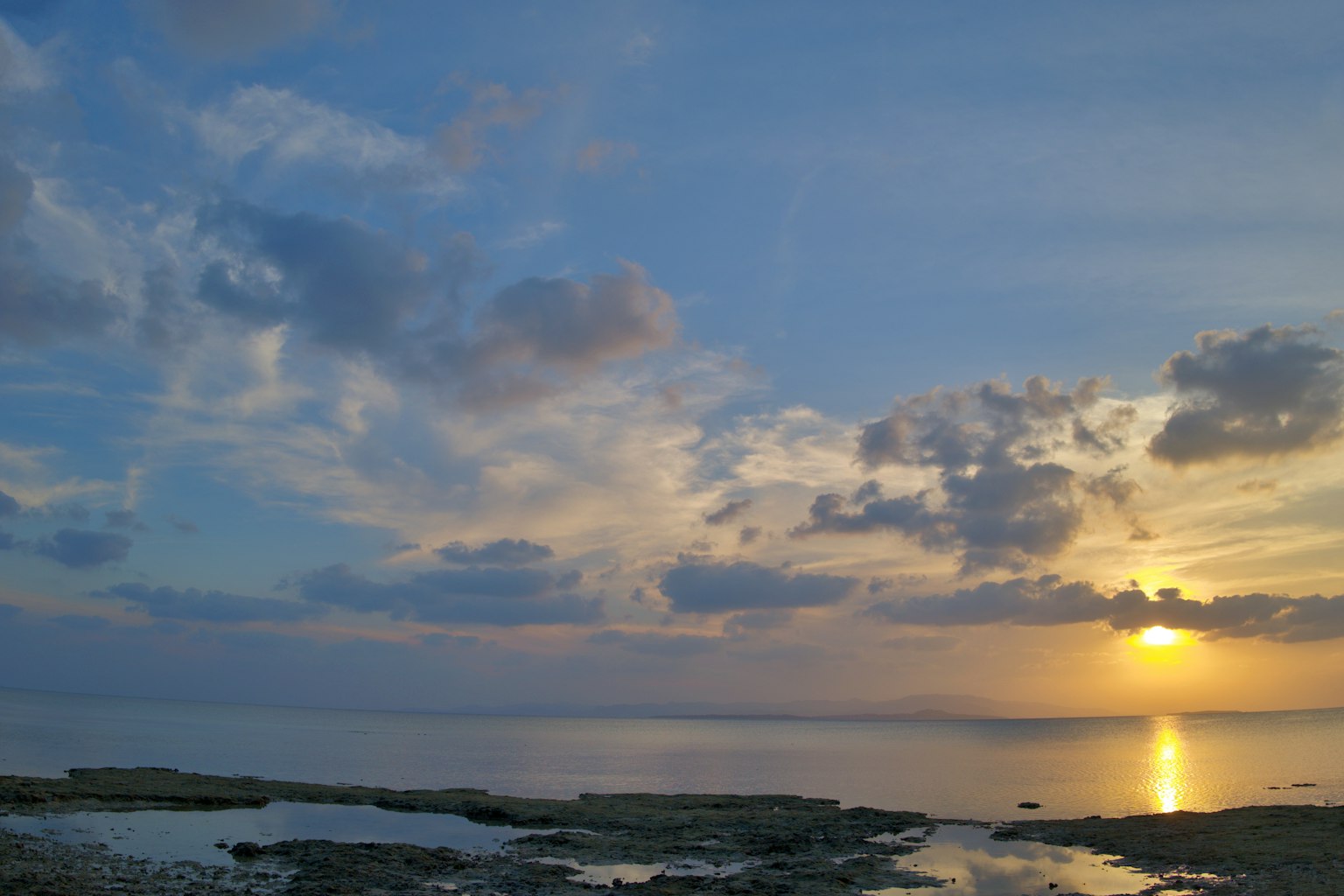 Hermoso atardecer sobre el océano con cielo azul y nubes, superficie del agua brillante