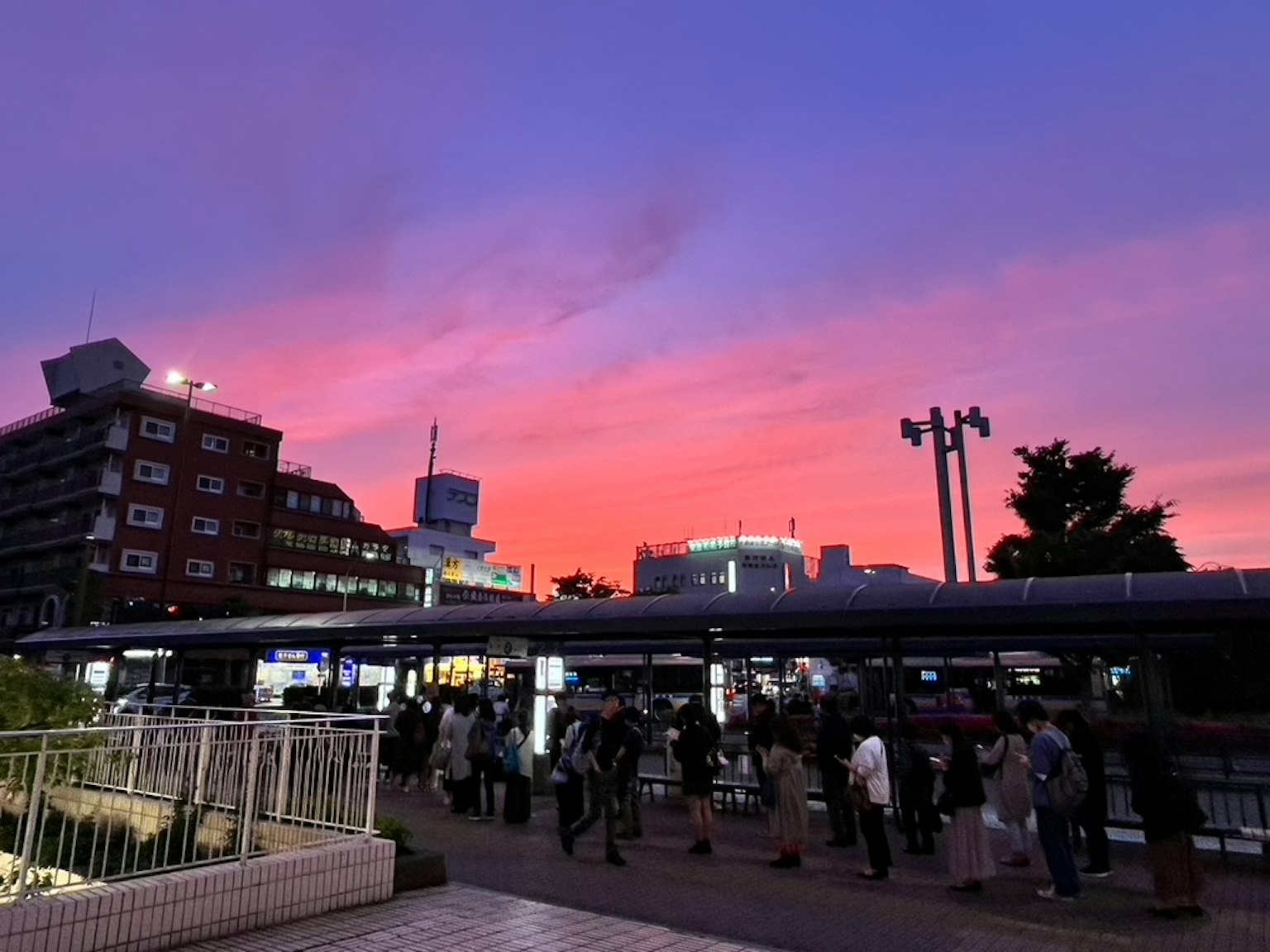 Cielo de atardecer sobre una estación de tren concurrida con gente