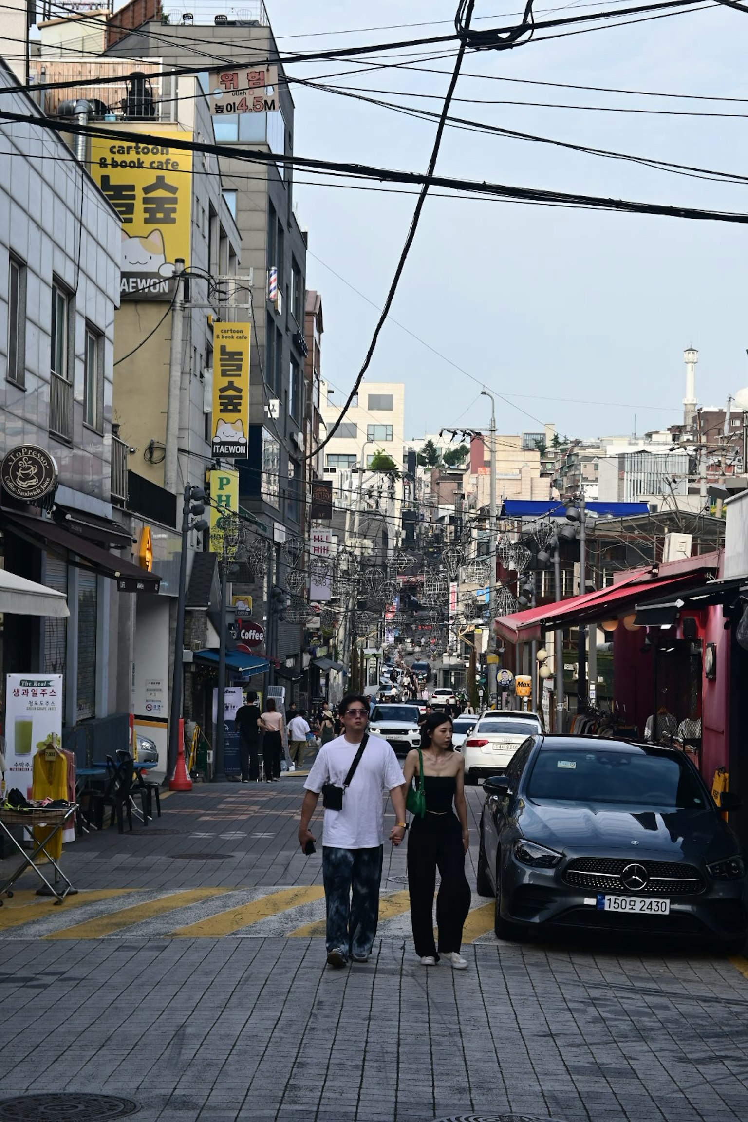 Couple walking in a bustling street with shops and power lines