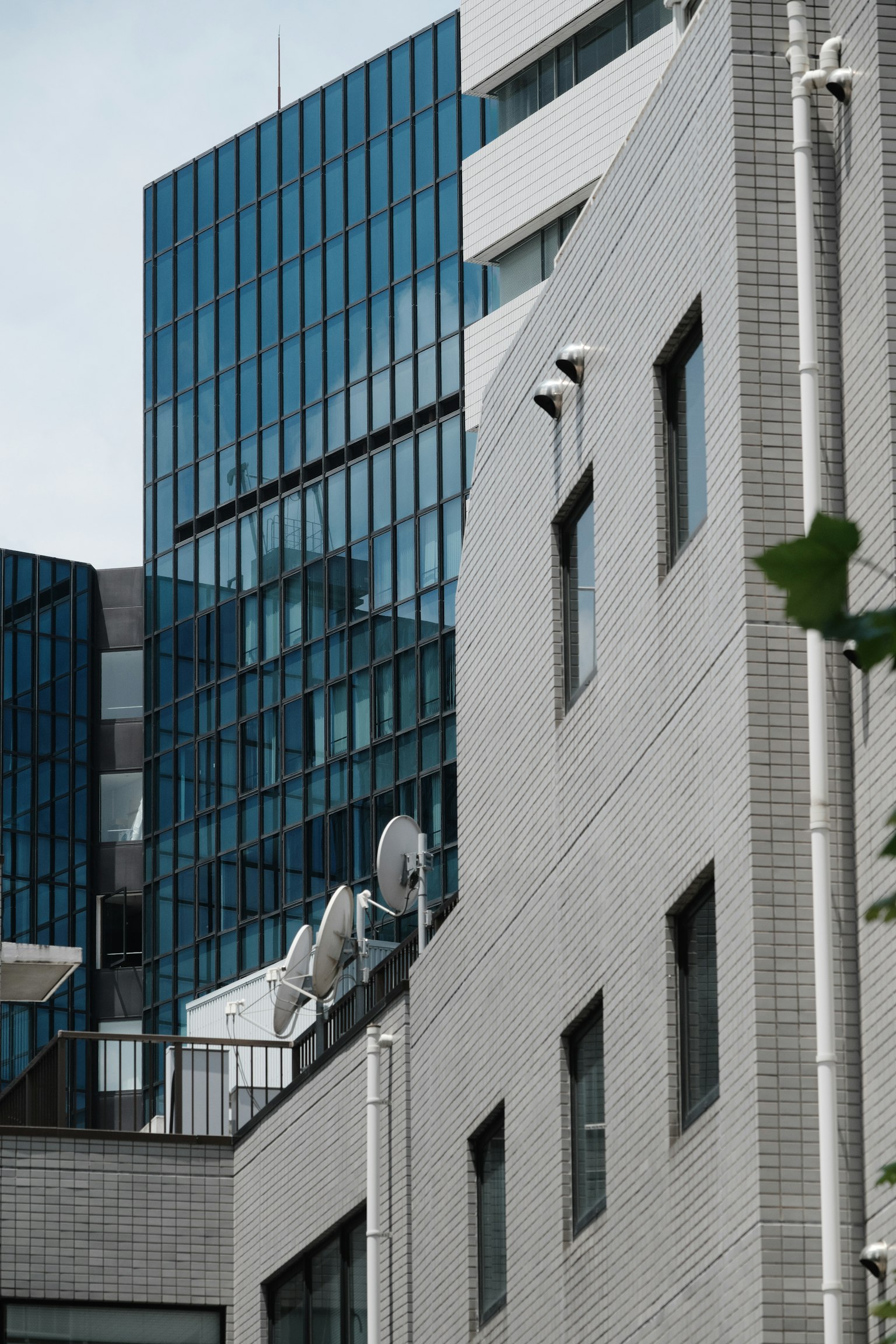현대 건물의 일부를 보여주는 이미지 파란 유리 외관과 흰색 벽 구조