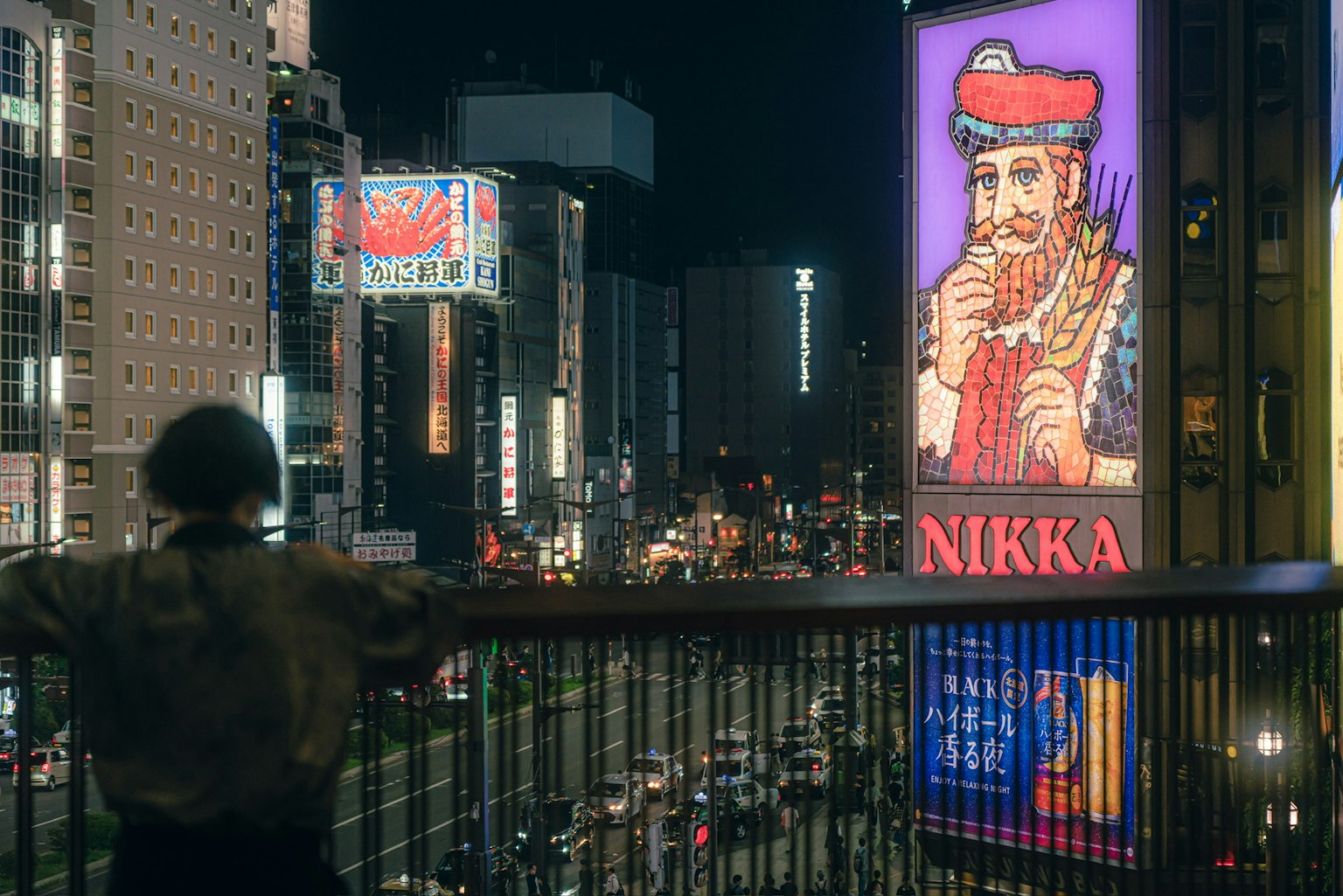 Persona che osserva un paesaggio urbano affollato di notte con pubblicità vivaci