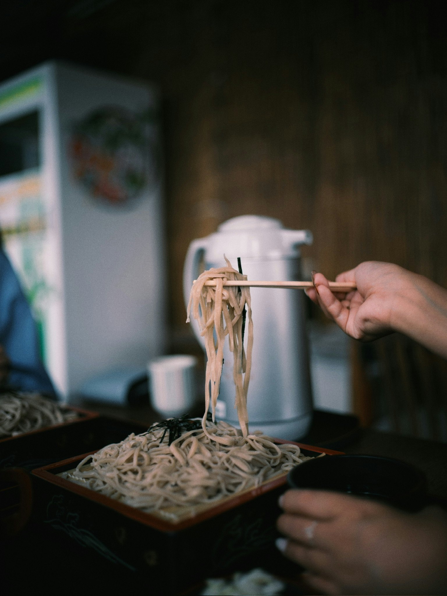 手で麺をつまむ蕎麦の調理風景