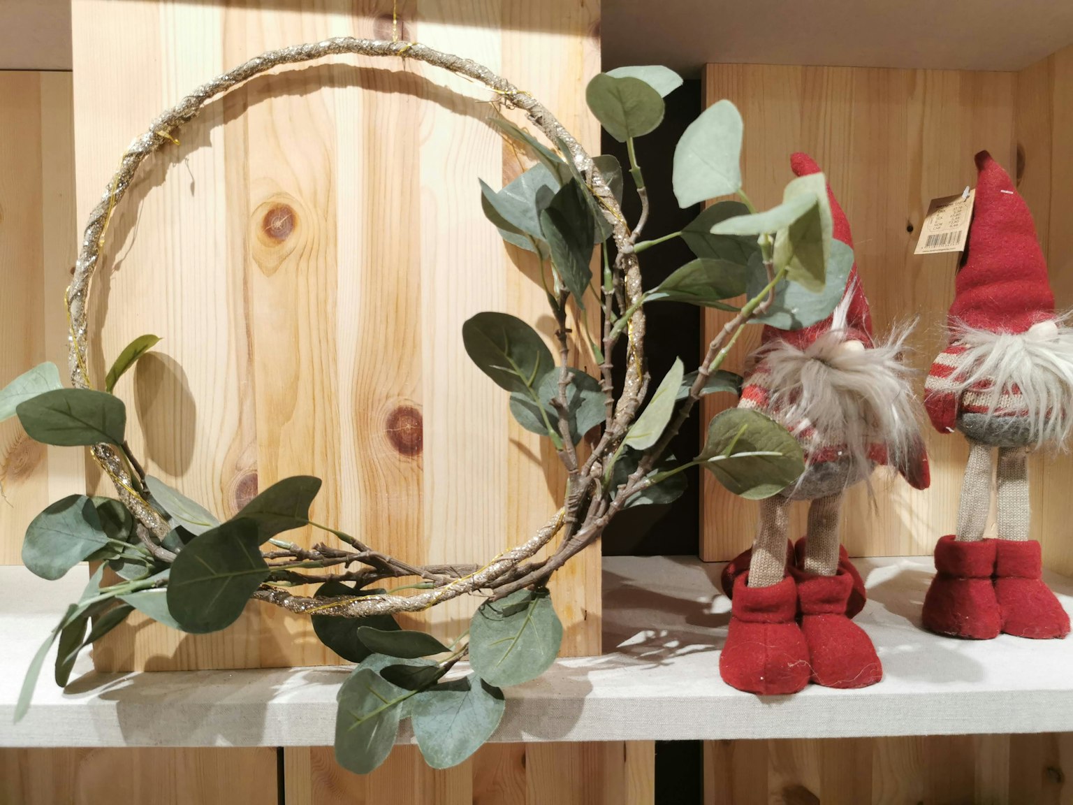 Una ghirlanda fogliosa posizionata davanti a una scatola di legno accanto a piccole figure con scarpe rosse