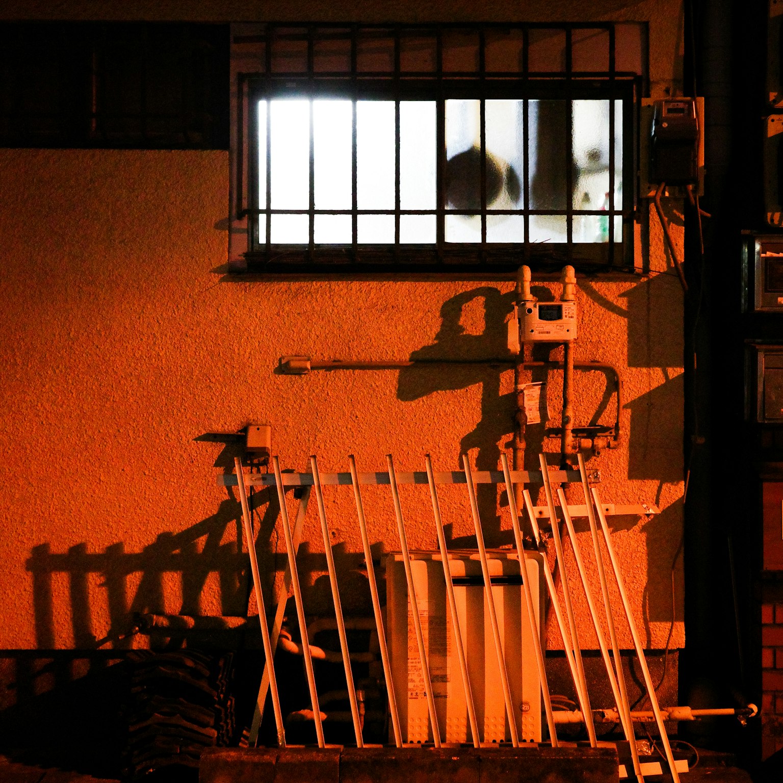 Escena nocturna con sombras de una ventana y una pared naranja