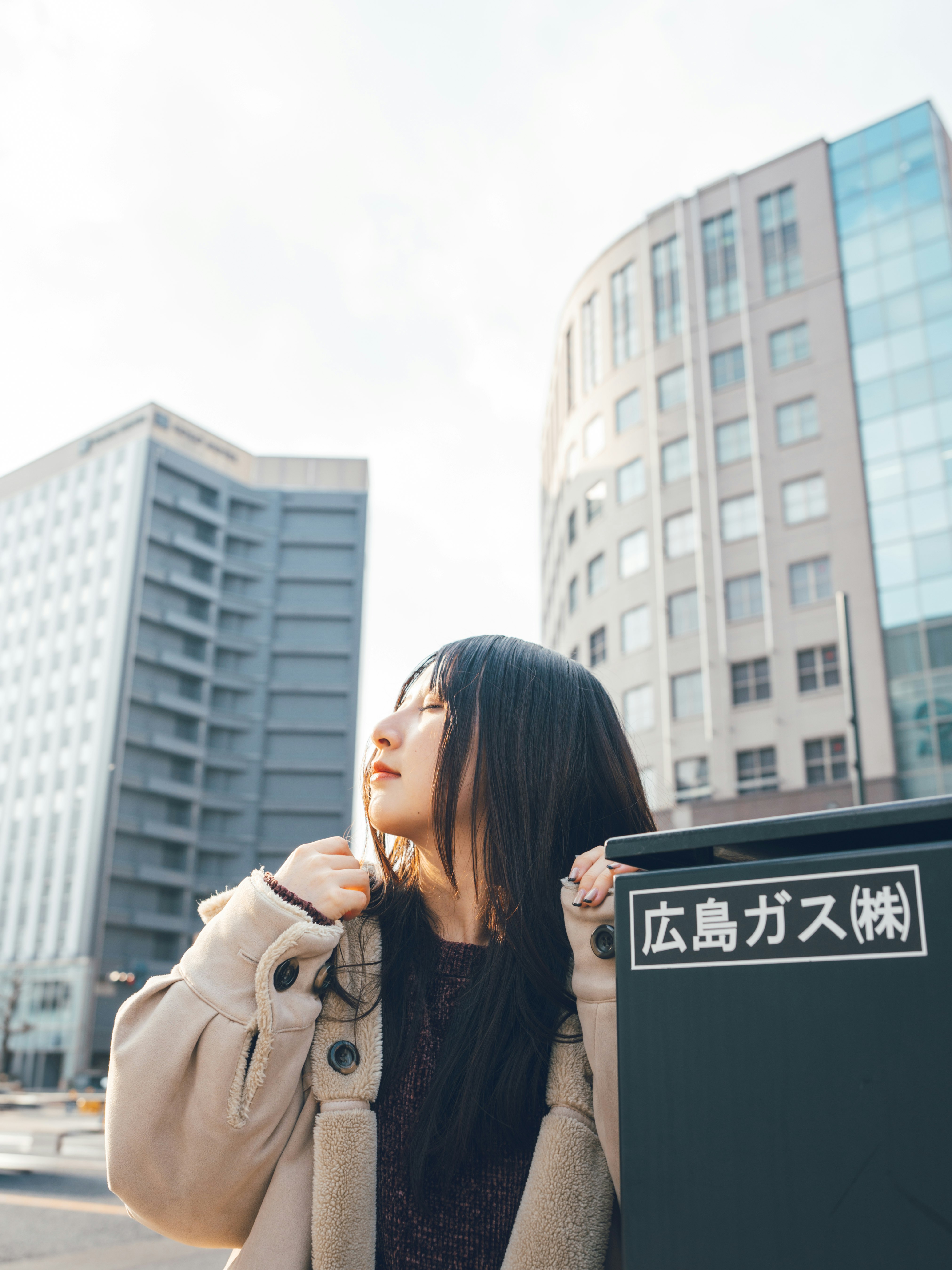 在“广岛燃气”标牌前手持燃气钢瓶的女性