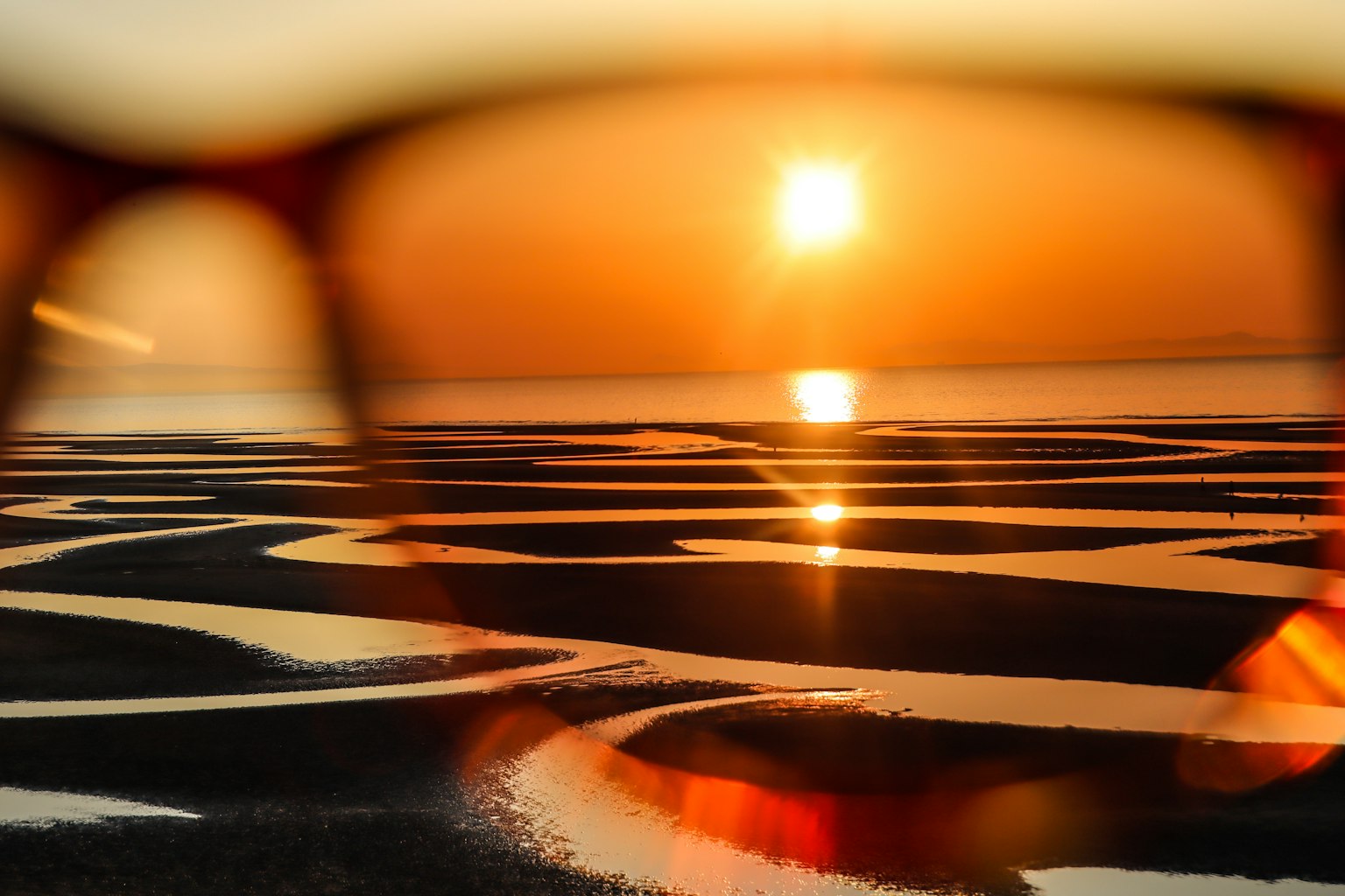 Tramonto che si riflette sull'acqua visto attraverso occhiali
