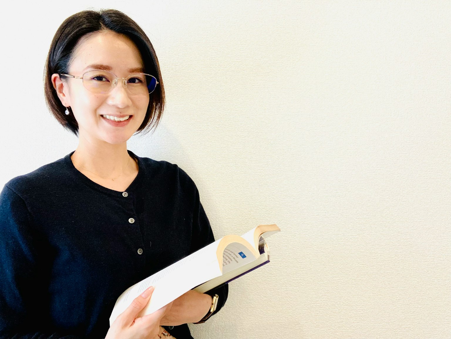 一位女性在简单背景下微笑着拿着一本书