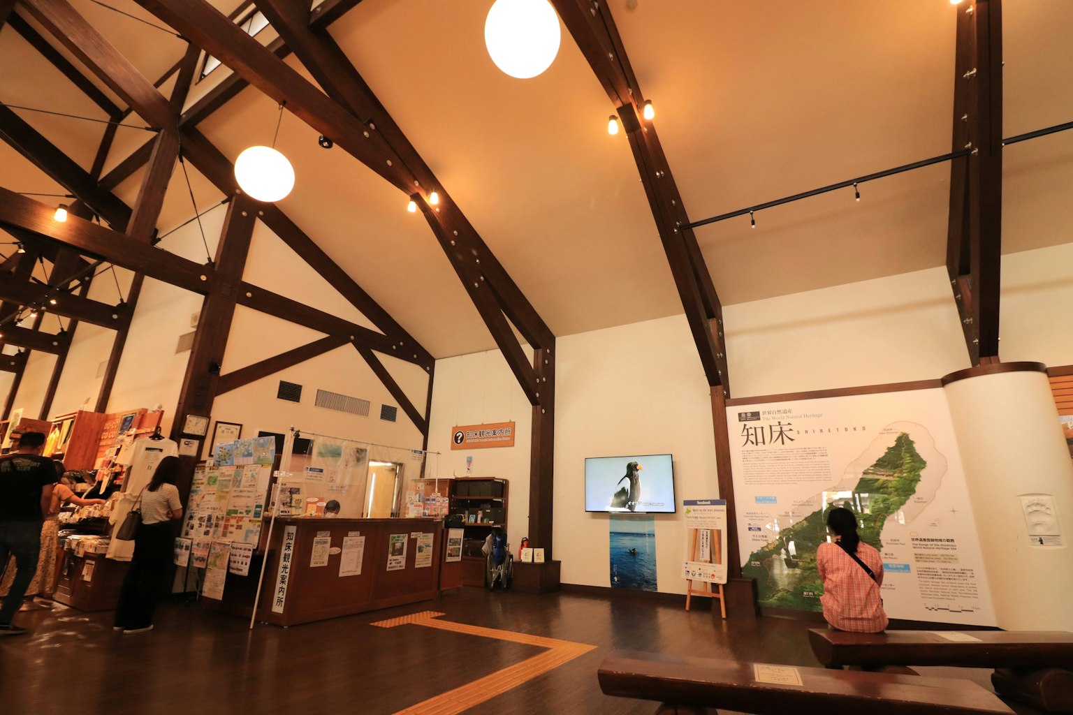 Salle d'exposition avec des poutres en bois et des lumières vives présentant des visiteurs
