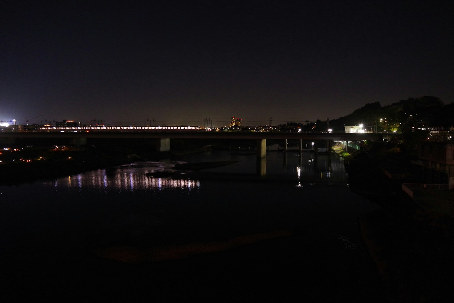 夜の河川と橋の景色、遠くに都市の明かりが見える