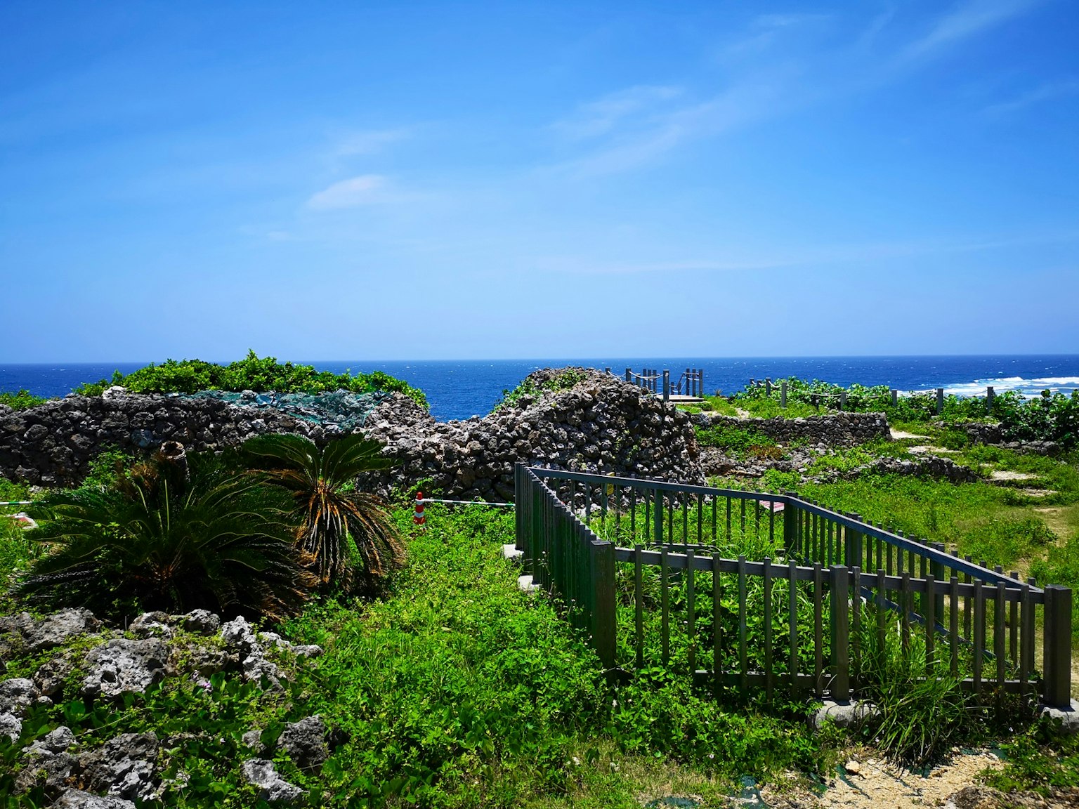 Lush green landscape with ancient stone ruins and a view of the blue sky and ocean