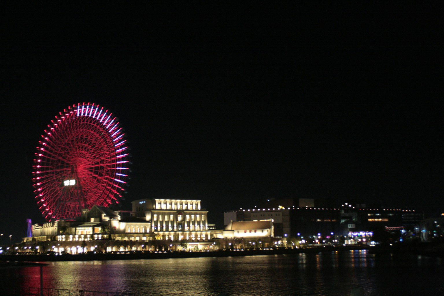 Belle vue nocturne avec une grande roue et des bâtiments au bord de l'eau