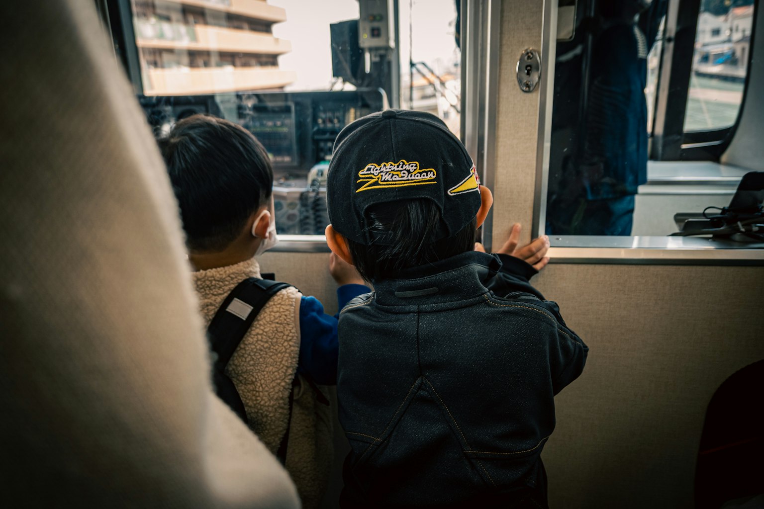 Zwei Kinder, die mit dem Rücken zum Fenster eines Busses schauen