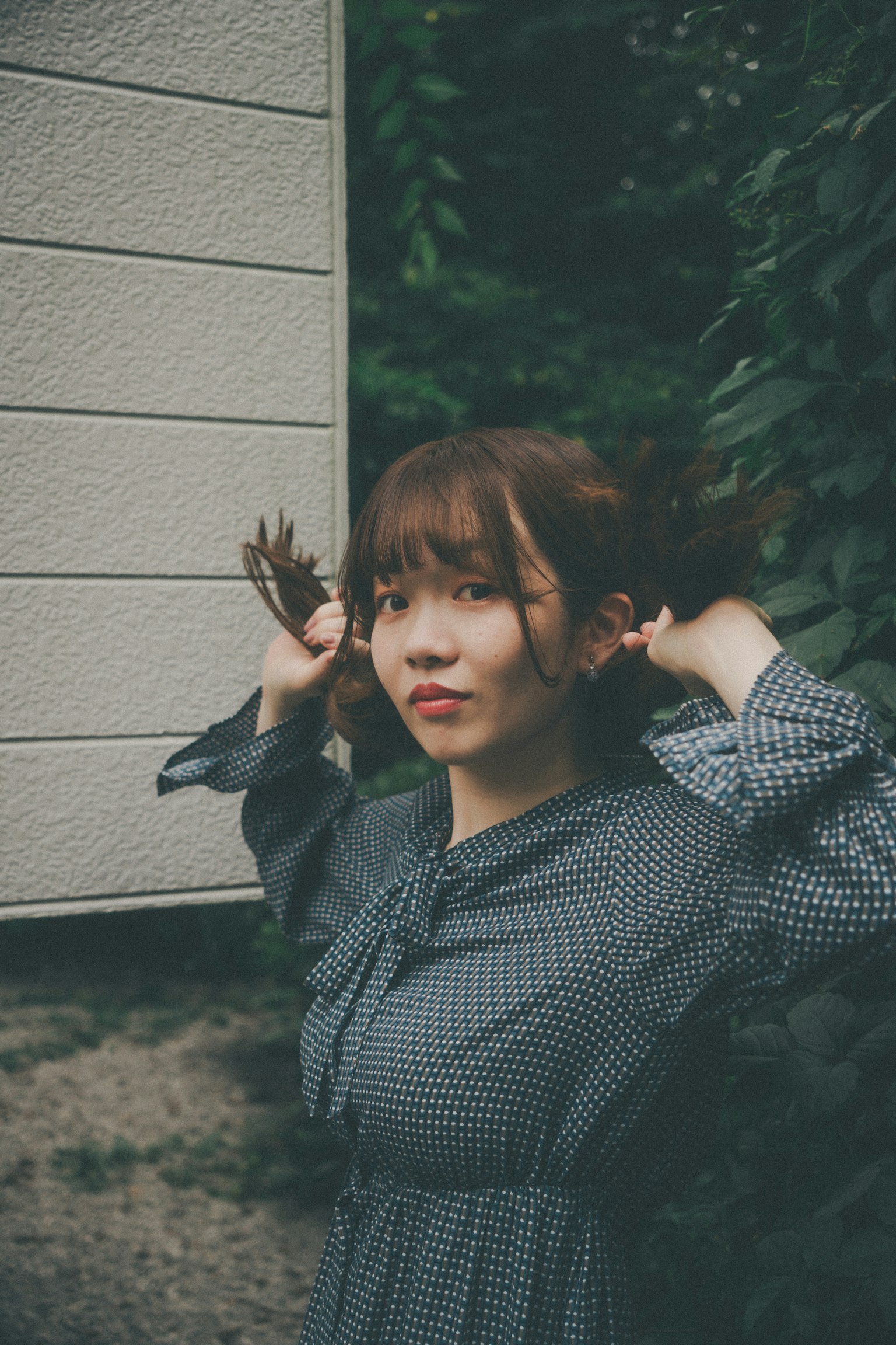 年轻女性在绿色背景前整理头发