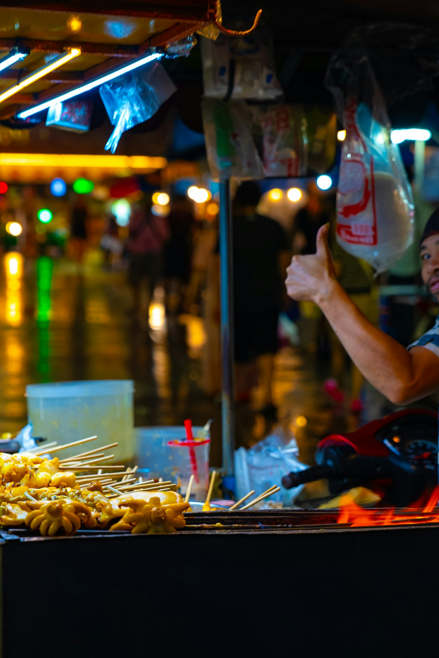 พ่อค้าข้างทางยิ้มให้กับกล้องขณะที่ขายของว่างในตอนกลางคืน